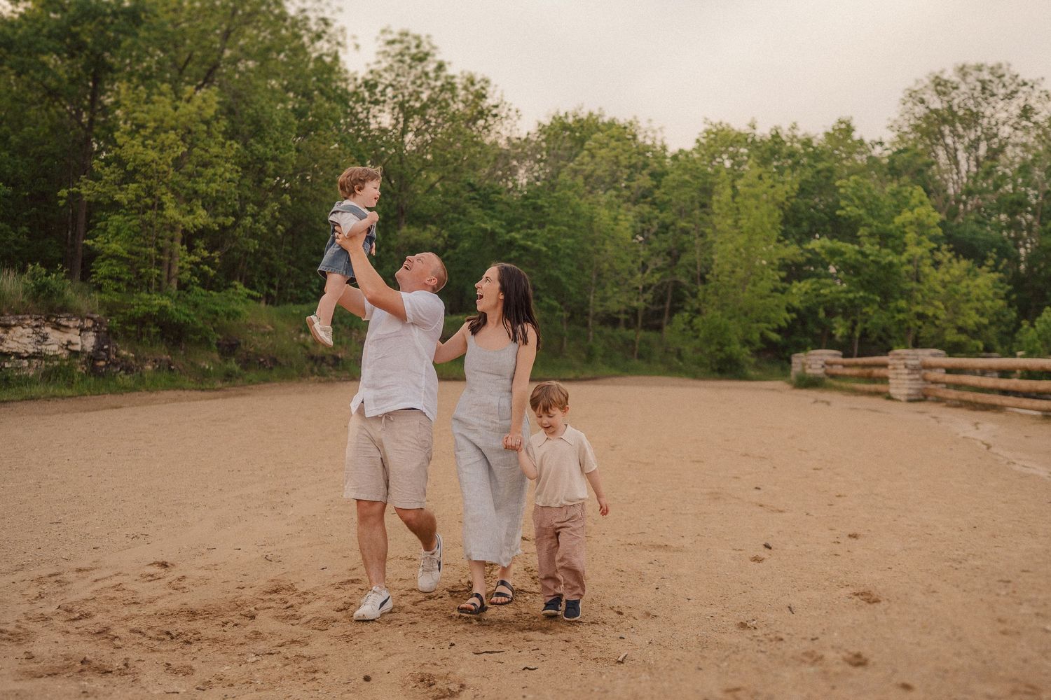 Wide angle view of family spending time together on sandy riverbank during sunset.
