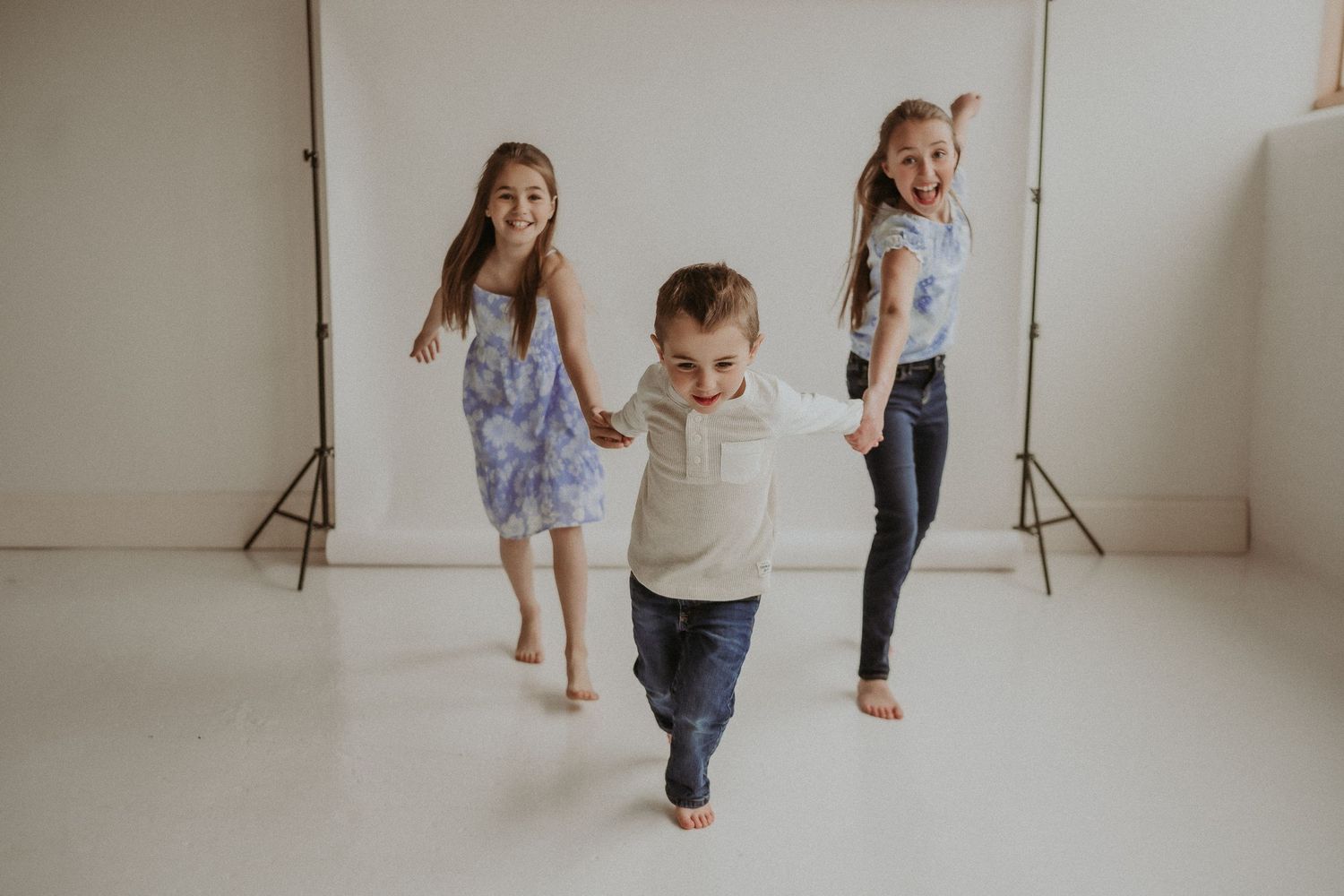 Three children dancing and playing in white studio setting.