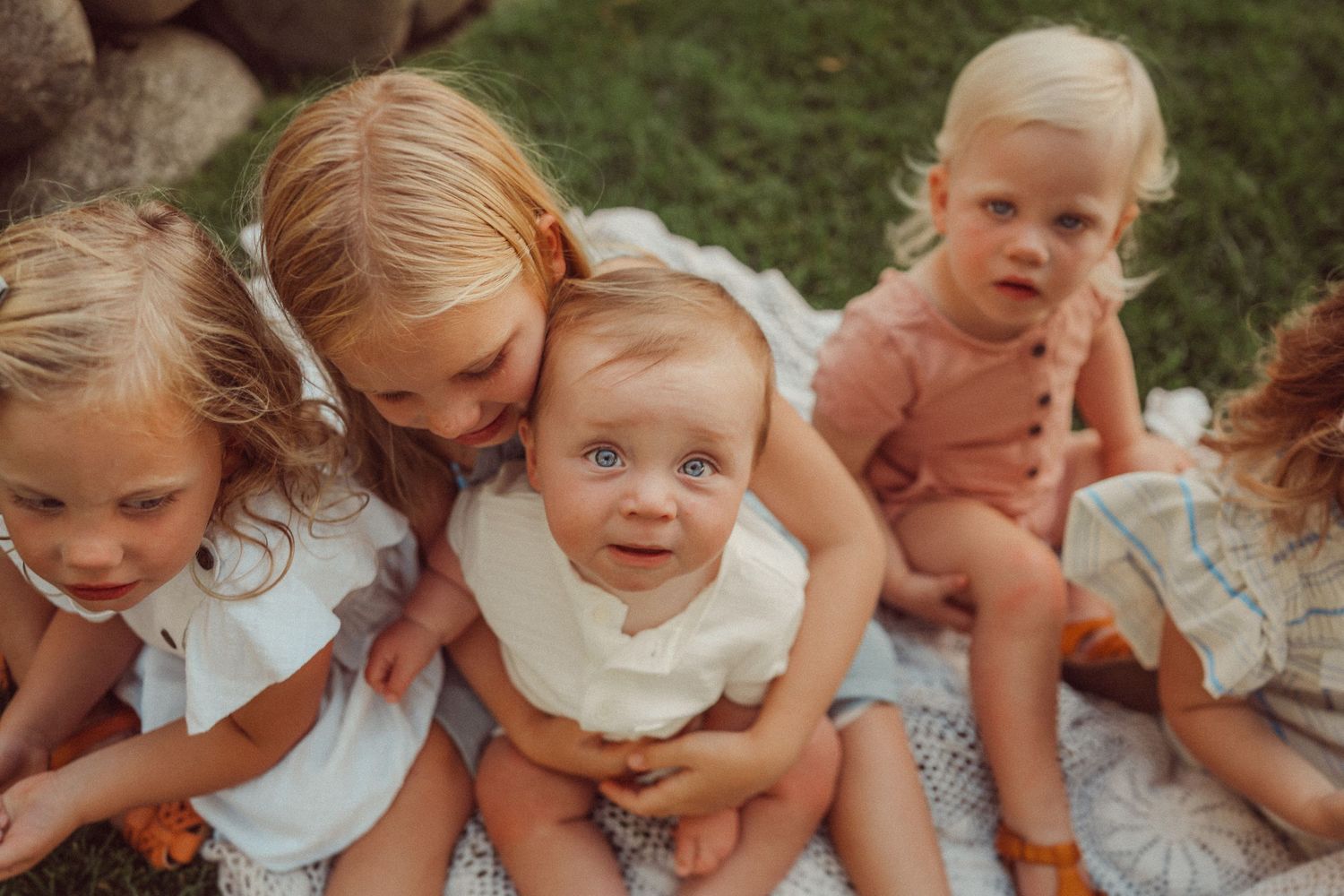 Close-up portrait of young children sitting together in white and neutral colored clothing.