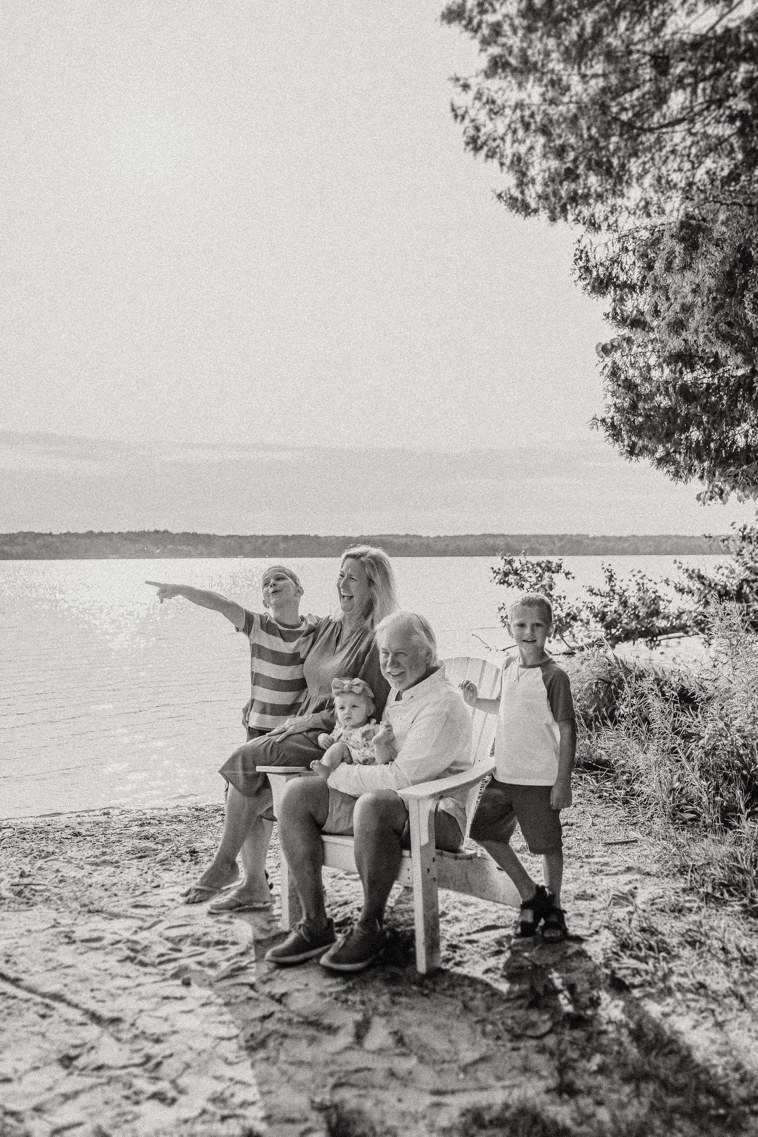 Multi-generational family gathering on a lakeside beach during golden hour.