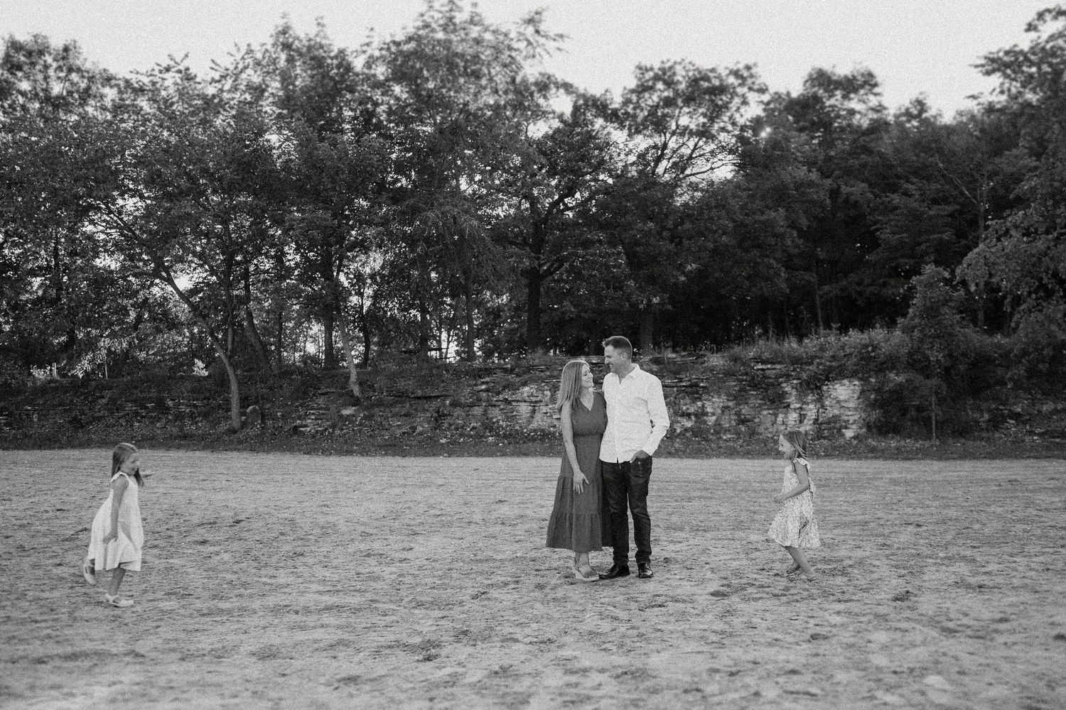 A black and white photo of a family standing together in an open field.