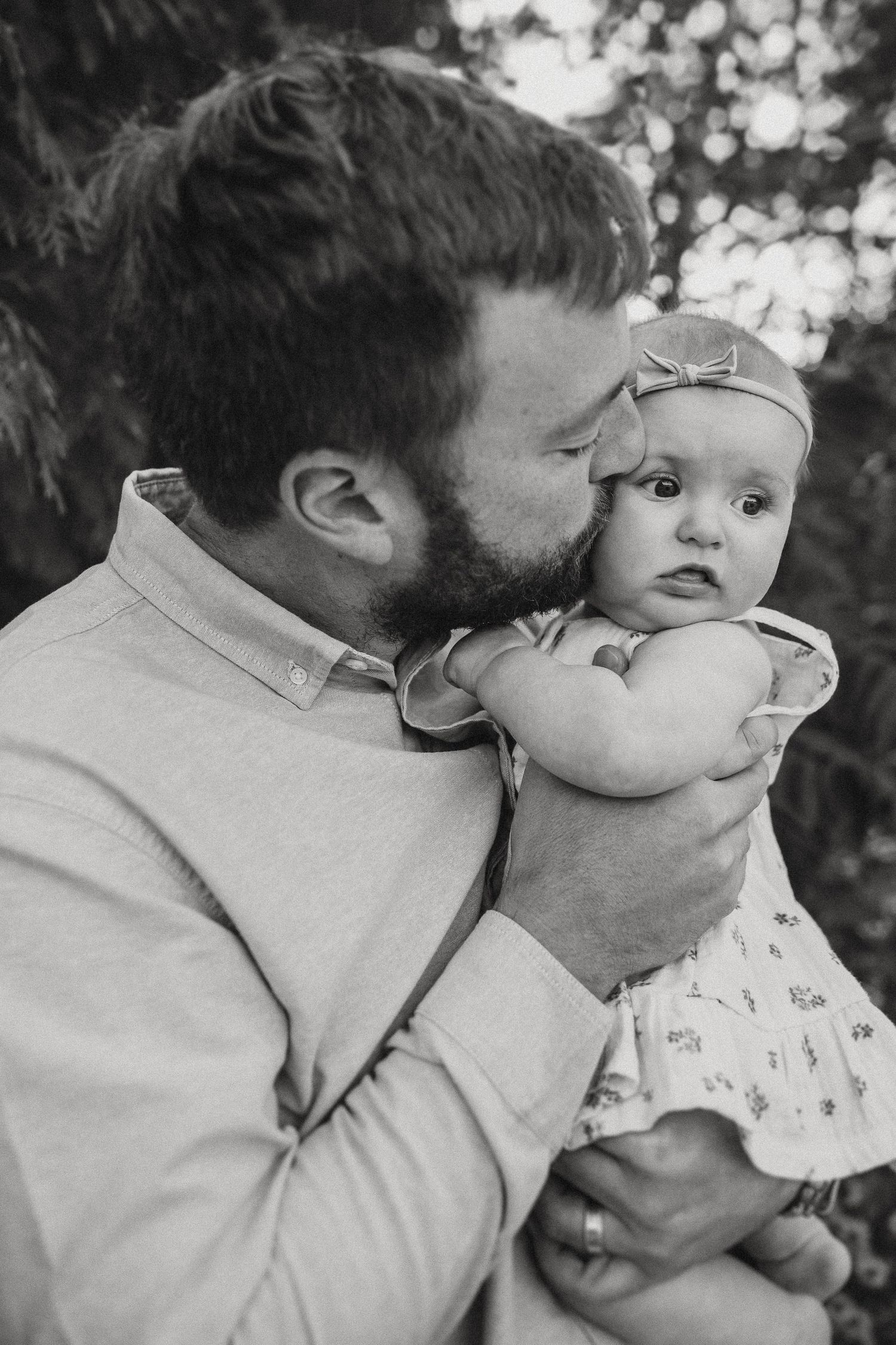 A touching black and white moment between parent and baby wearing a small bow headband.