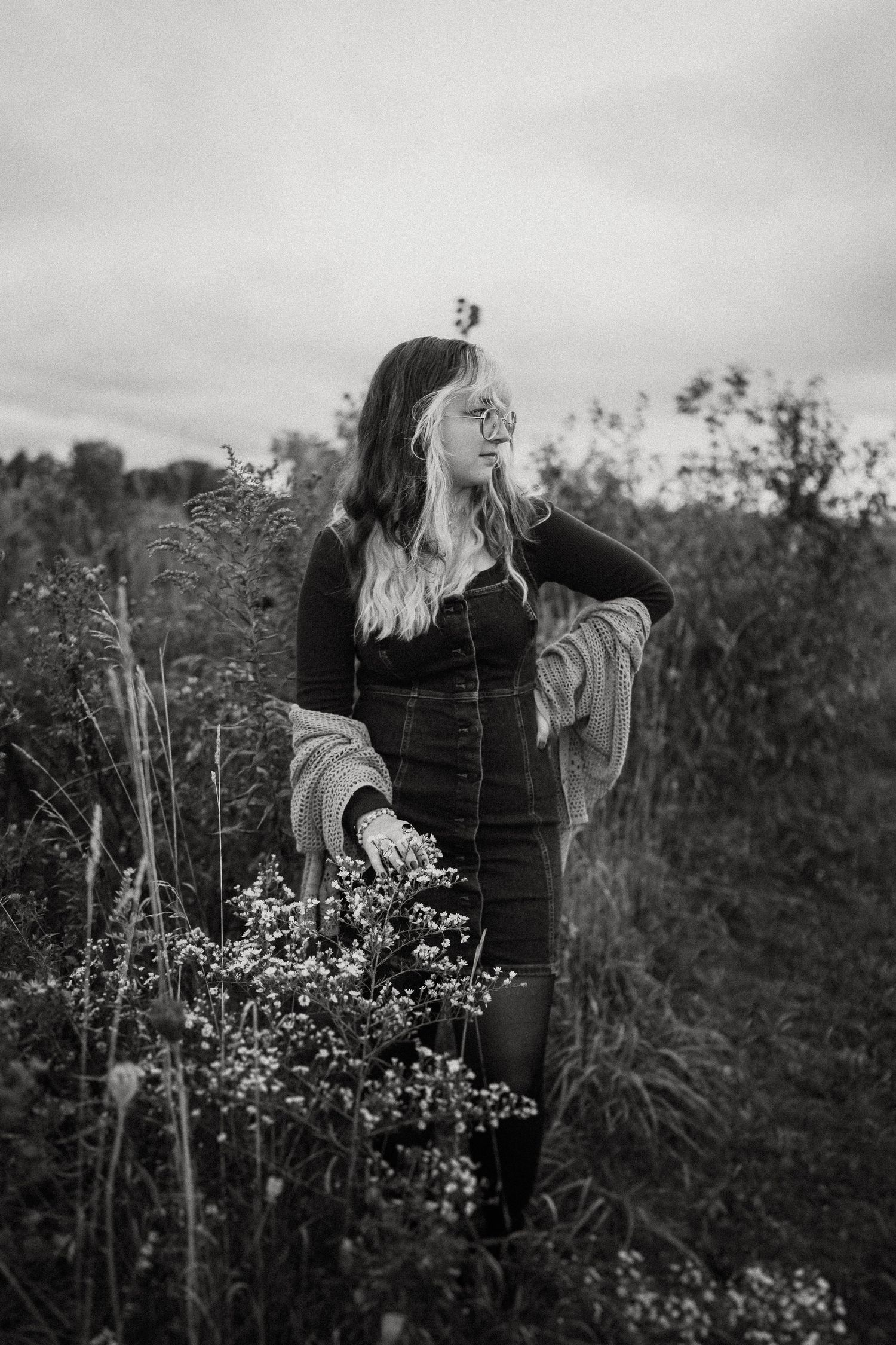 Artistic black and white portrait among tall grasses and wildflowers on overcast day.