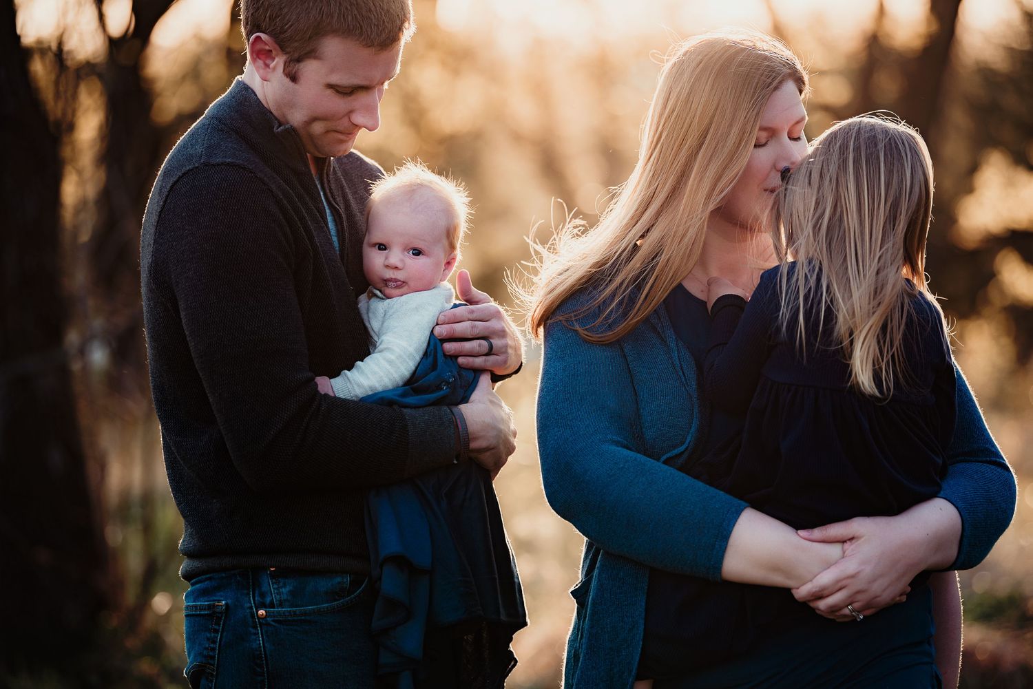 Golden hour family portrait in wooded setting during sunset.