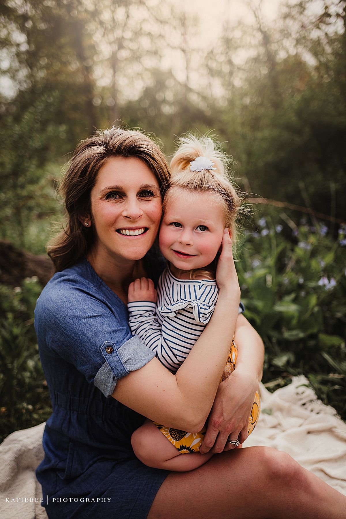 Warm outdoor portrait on a blanket with purple wildflowers in background.