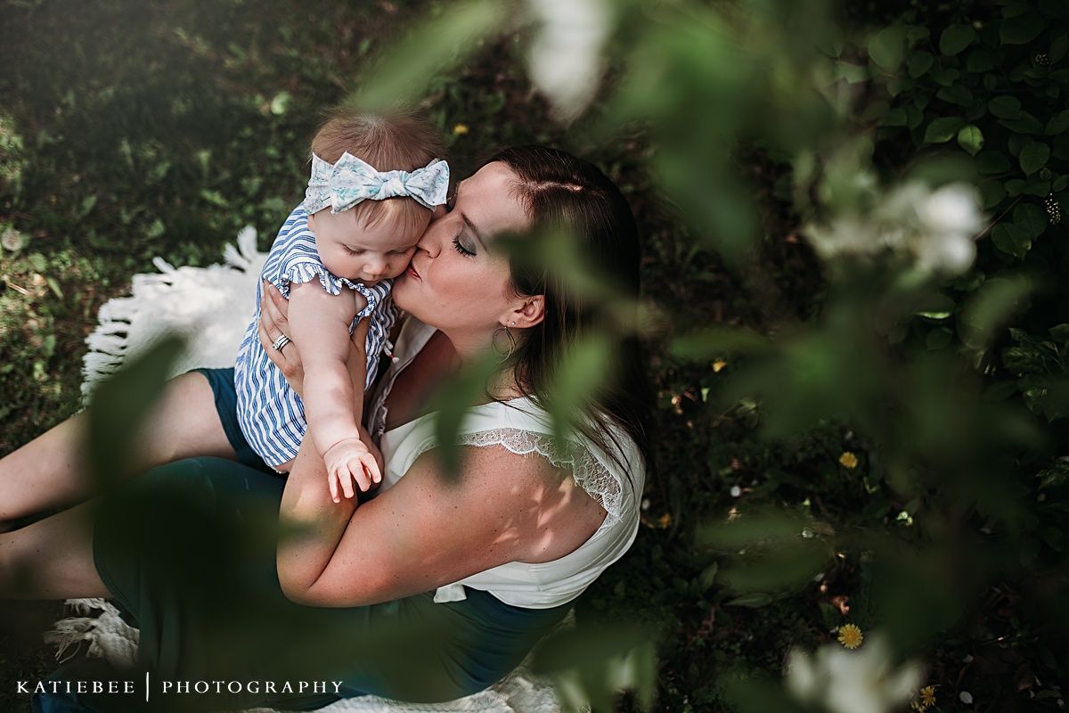 Overhead view of parent and baby sharing a tender moment surrounded by greenery.