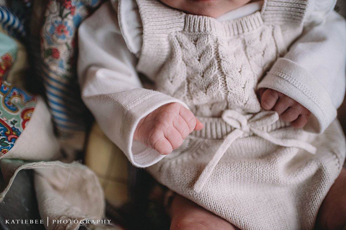 Detail shot of a baby wearing a cozy cream cable knit sweater.
