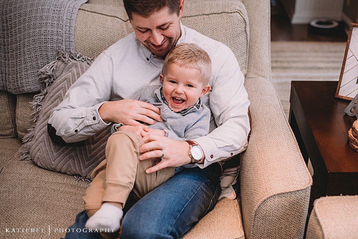 Joyful laughter shared during a playful moment on a beige couch.