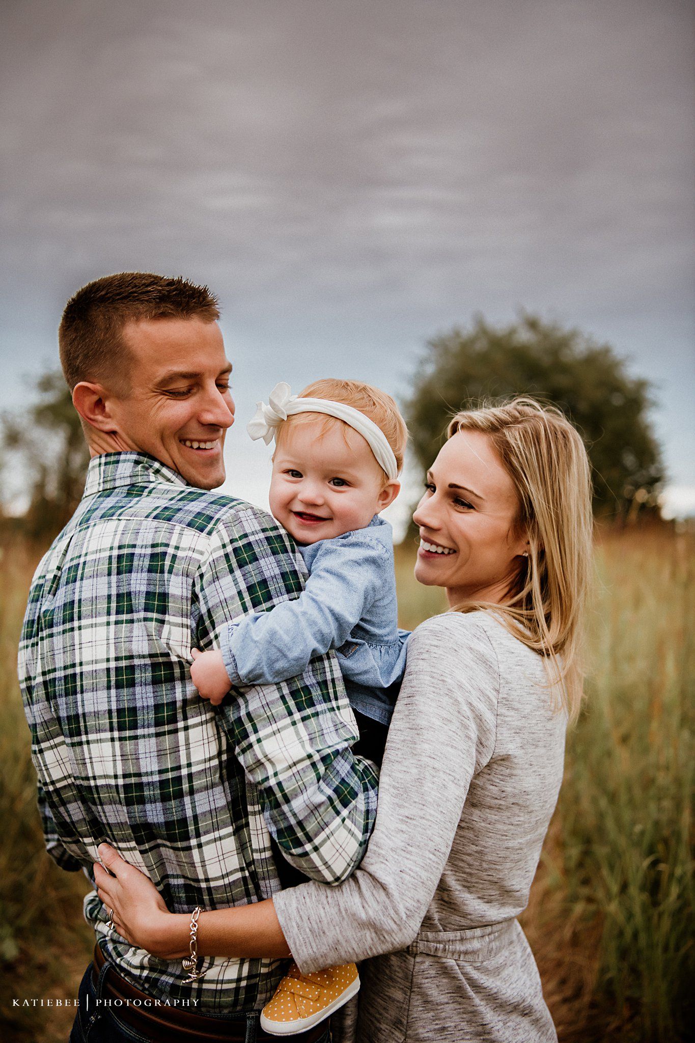 Happy candid family portrait taken in a rustic field setting at sunset.