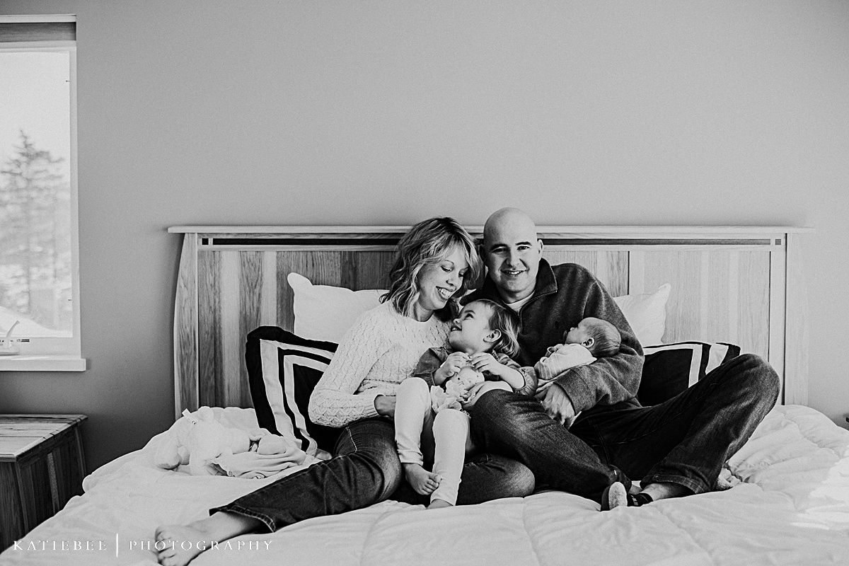 A family shares intimate moments together while relaxing on a bed in black and white.