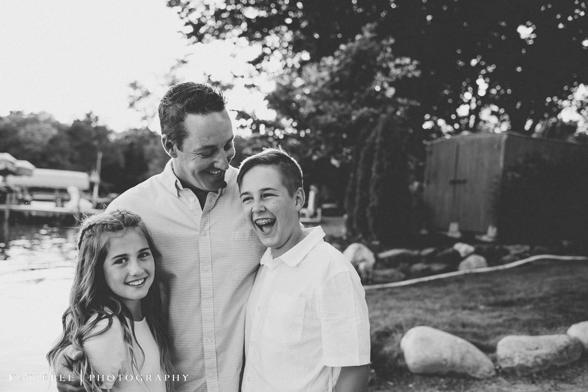 A black and white portrait of three people laughing together outdoors.