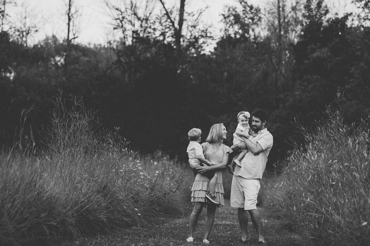 Black and white family portrait showing playful interaction in natural setting.