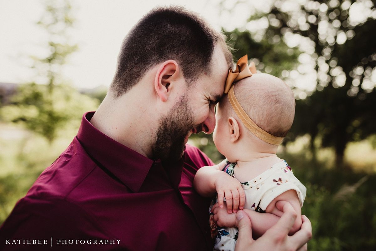 Sweet close-up candid portrait showing gentle interaction between adult and smiling baby.