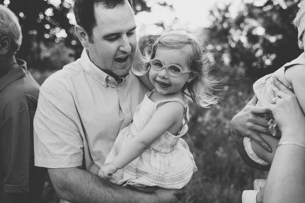 Black and white candid moment of family members sharing a laugh outdoors.