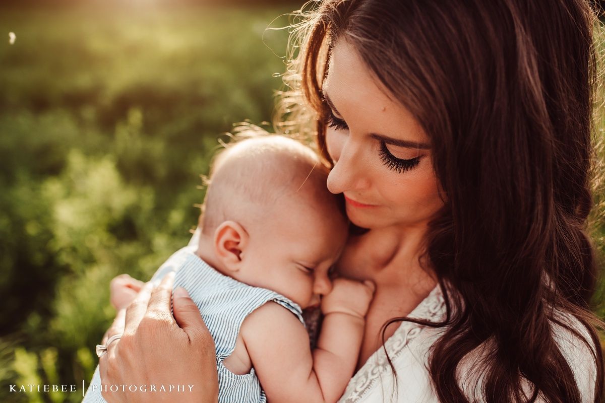 Tender moment between mother and baby in natural outdoor setting.