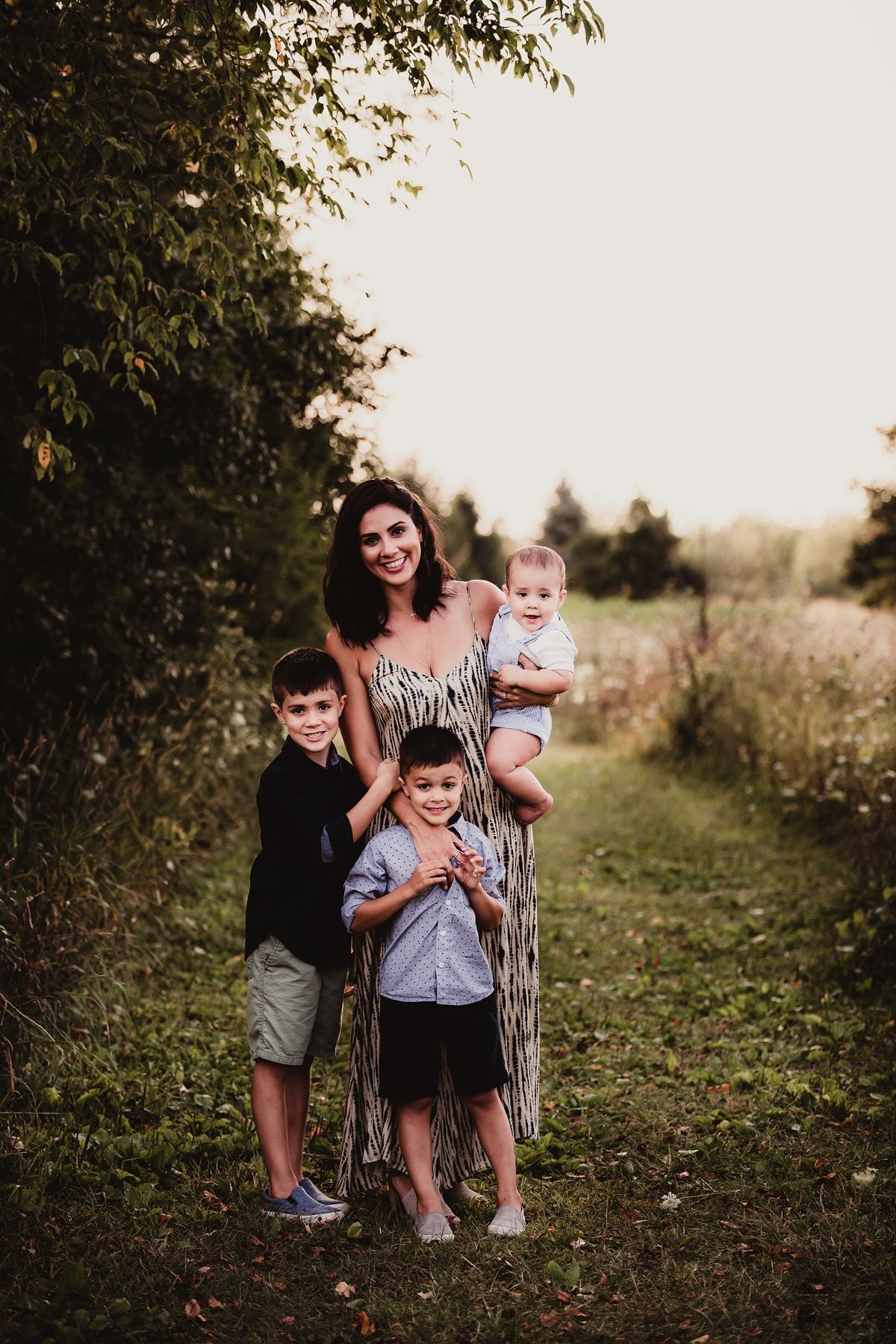 Family portrait on nature path with mother and children in casual attire.