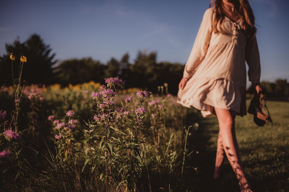 Artistic sunset photo of a flowing dress among pink wildflowers in a summer field.