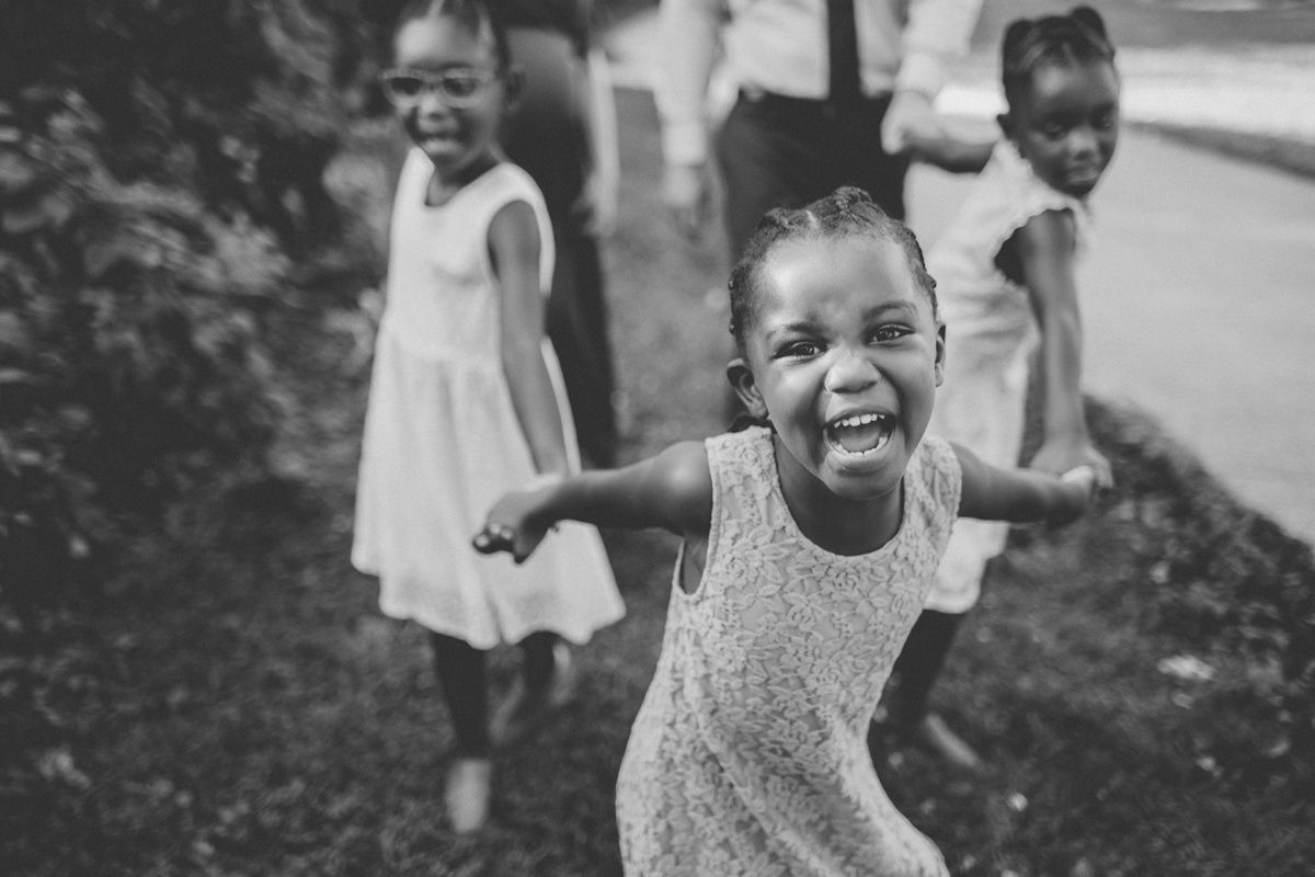 Black and white photo of children playing and running outdoors in summer dresses.
