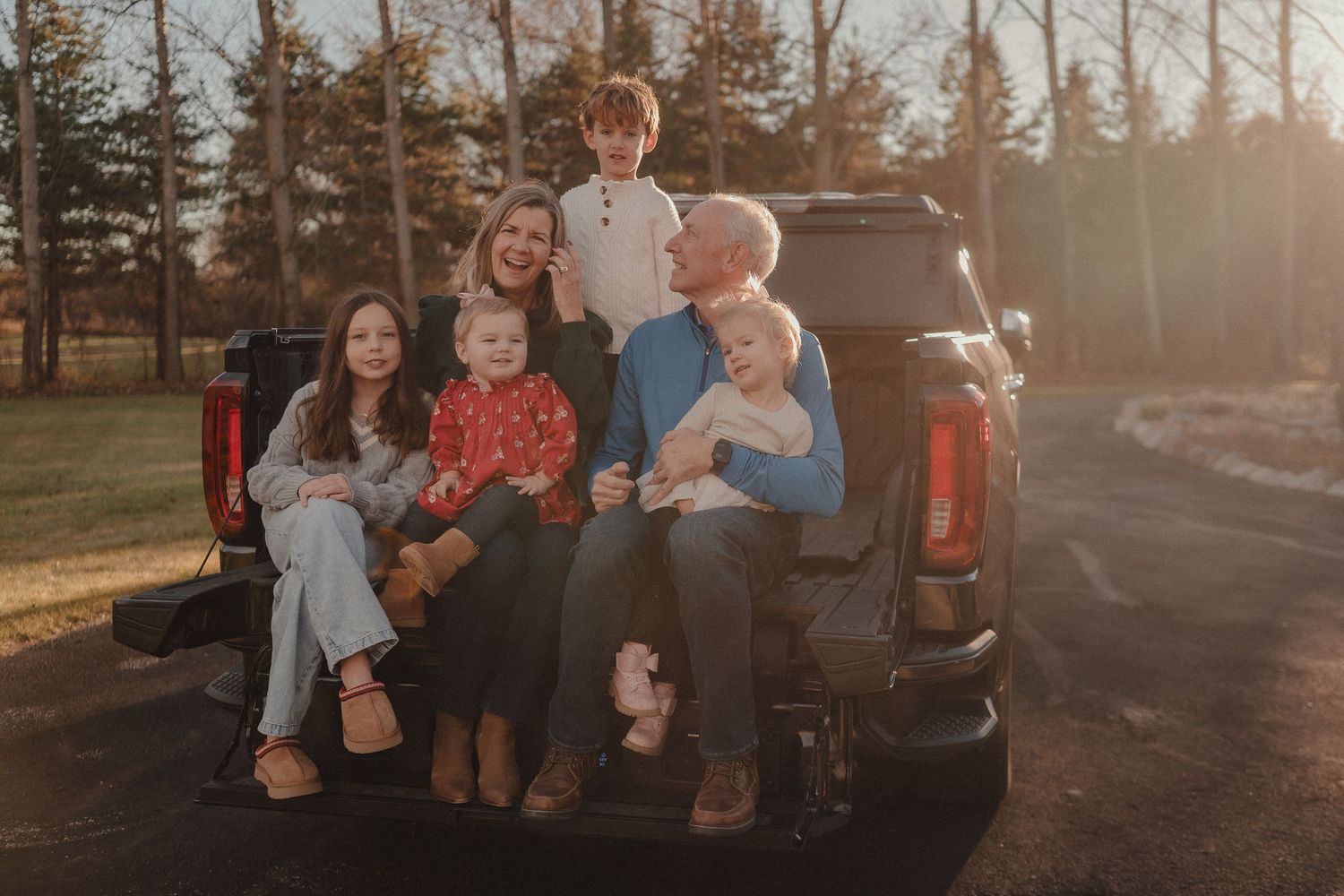 A family sits together in the back of a pickup truck during golden hour sunset.