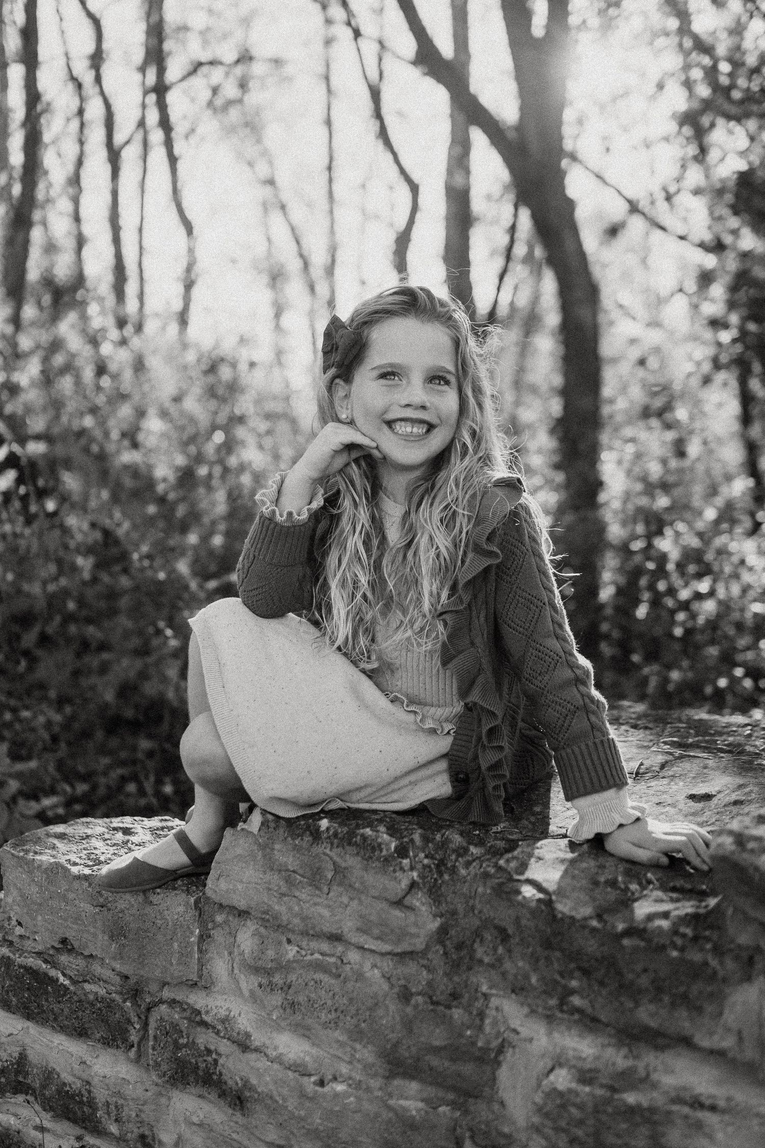 Black and white portrait series showing someone lying on a stone wall in a wooded outdoor setting.