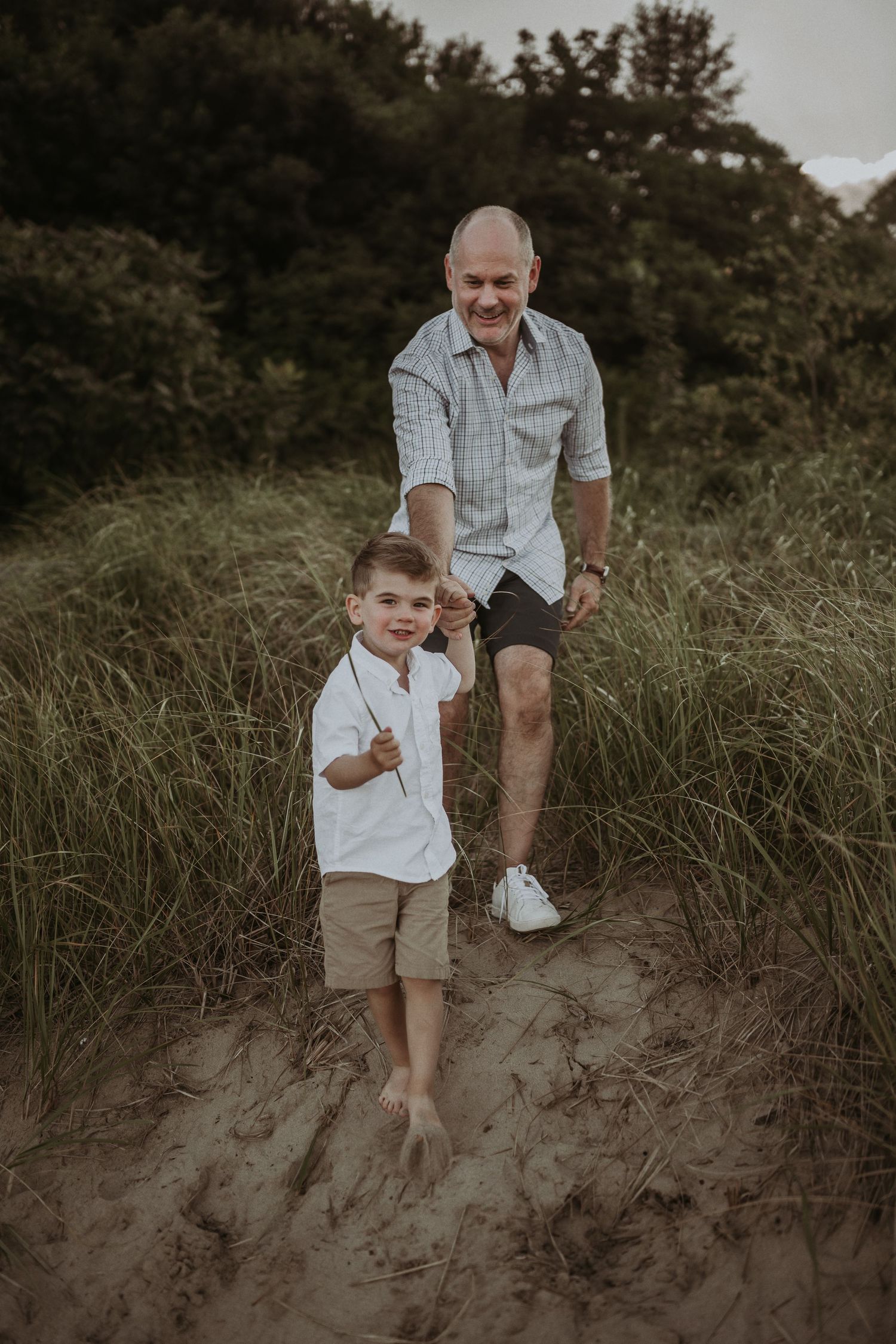 Two people walking together on sandy dunes at sunset with matching outfits.