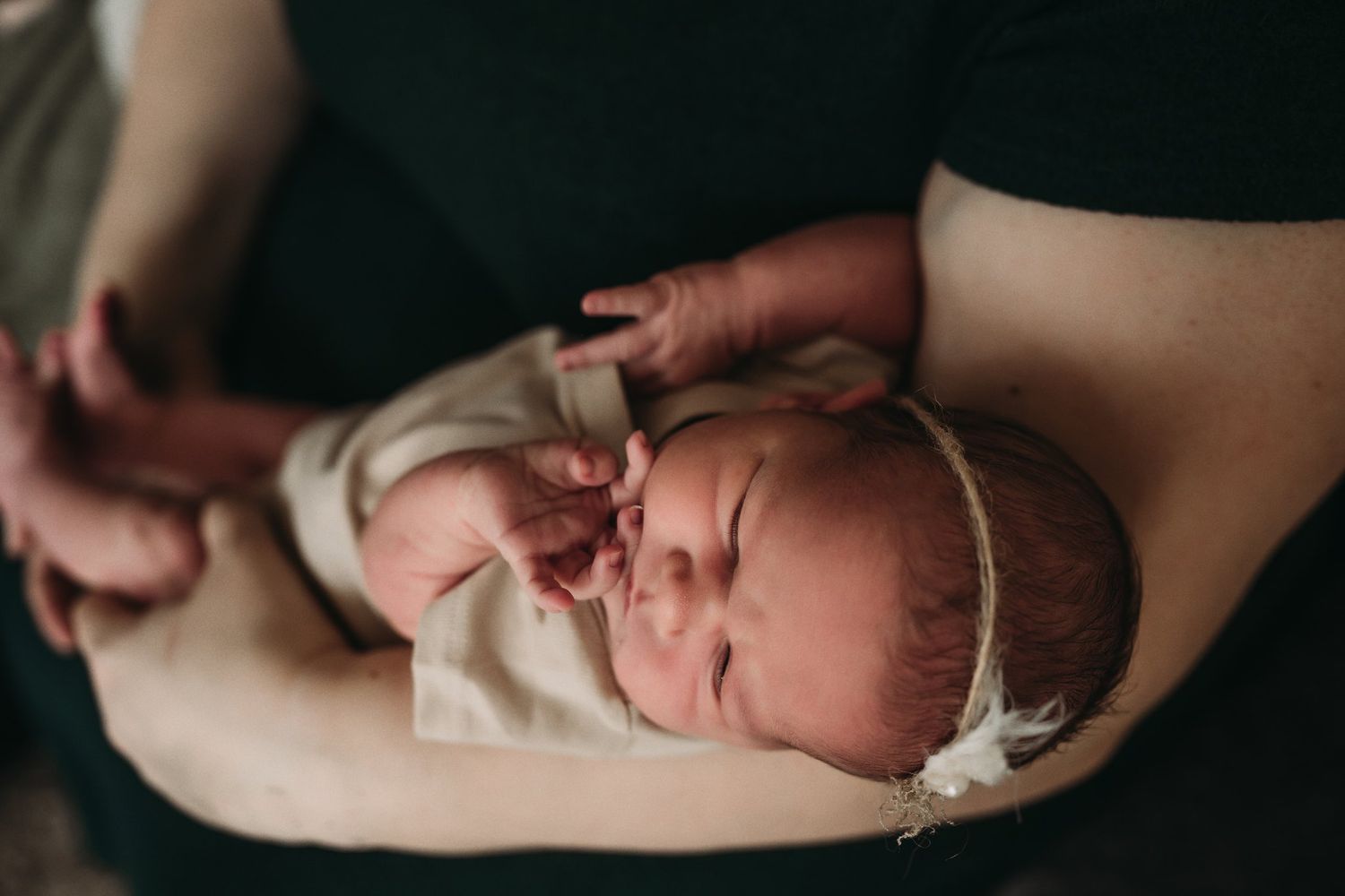 Newborn baby sleeping peacefully in white wrap with headband.