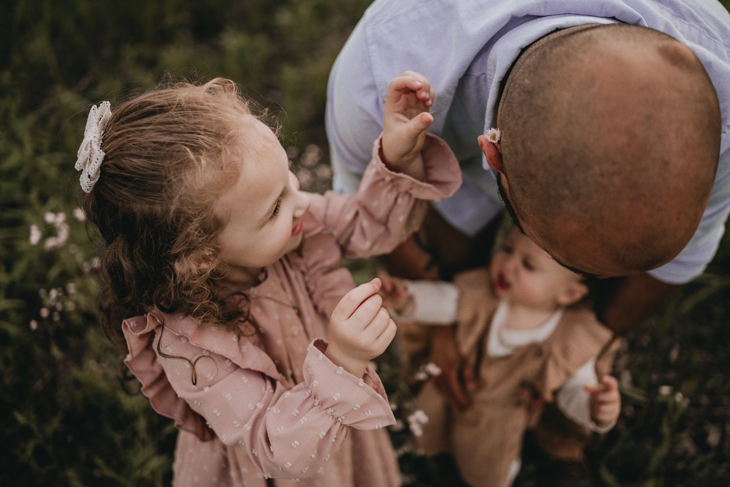 An intimate family moment captured among blooming wildflowers in a field.