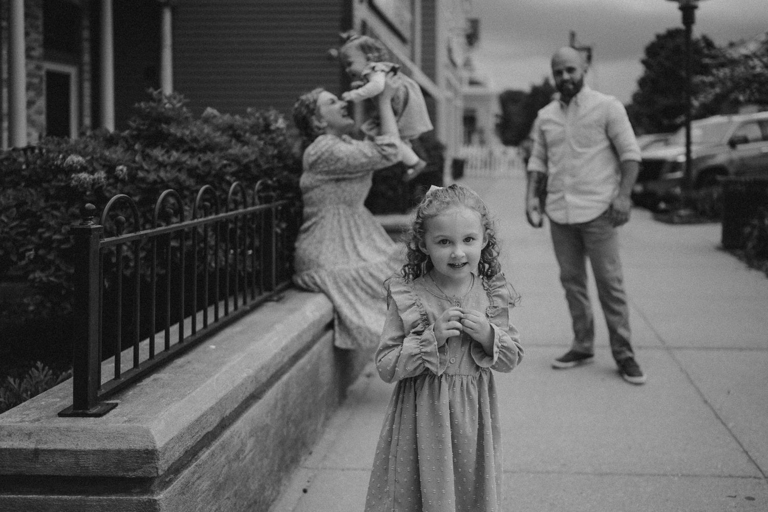 A black and white street scene showing playful interactions between family members.