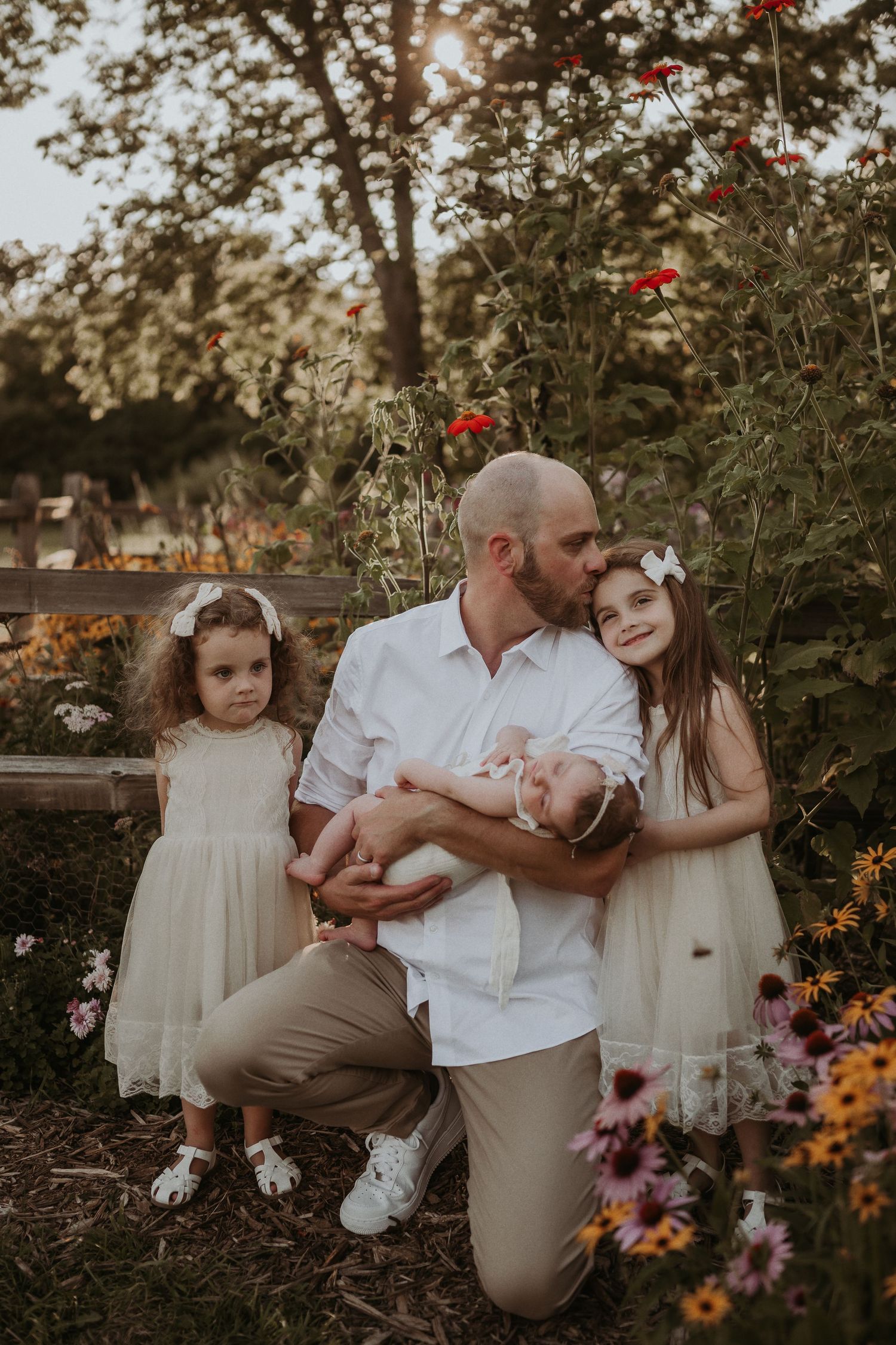 A beautiful family portrait in a flower garden with white dresses and warm sunset lighting.