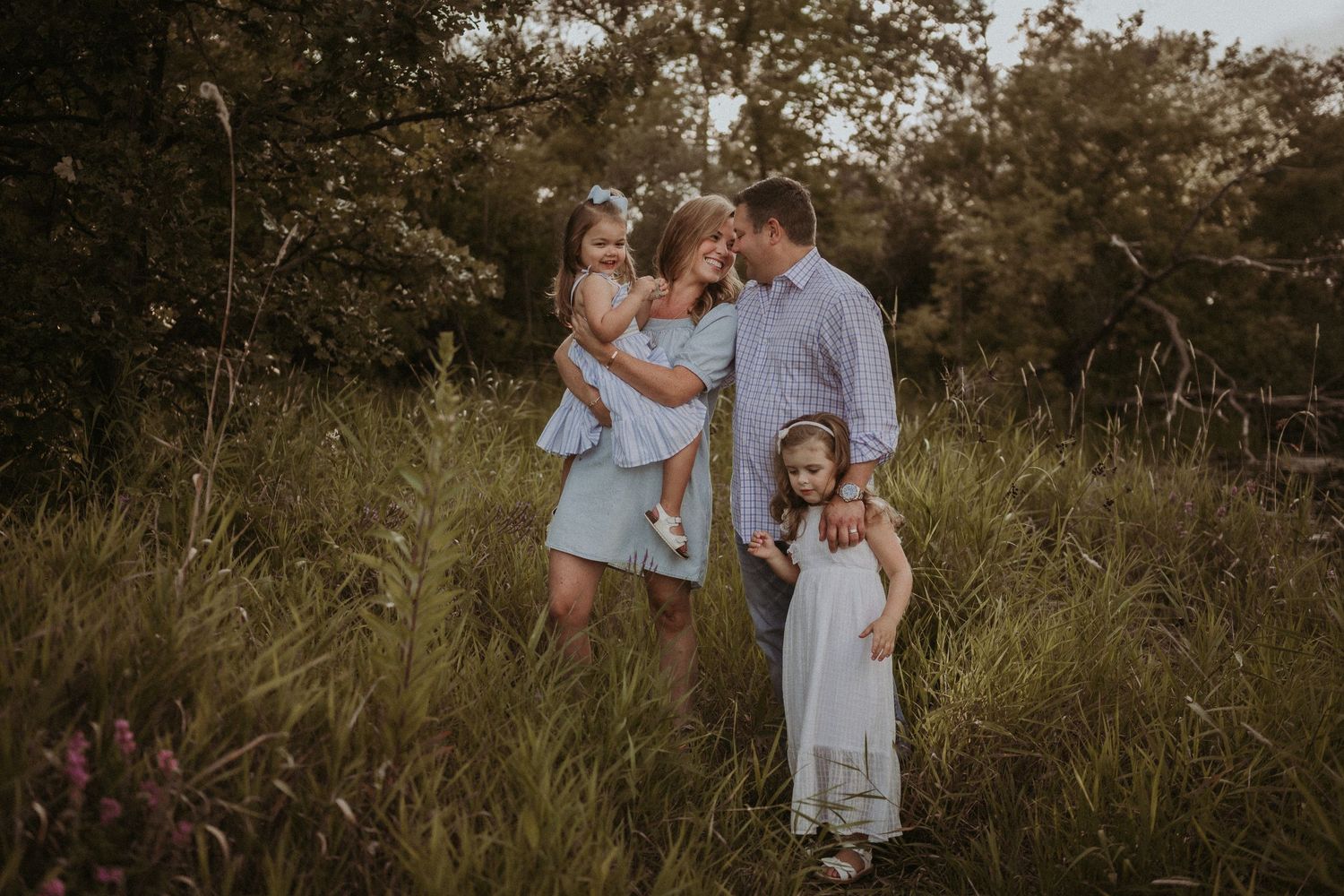 A family lifestyle portrait session in a golden sunlit meadow at dusk.