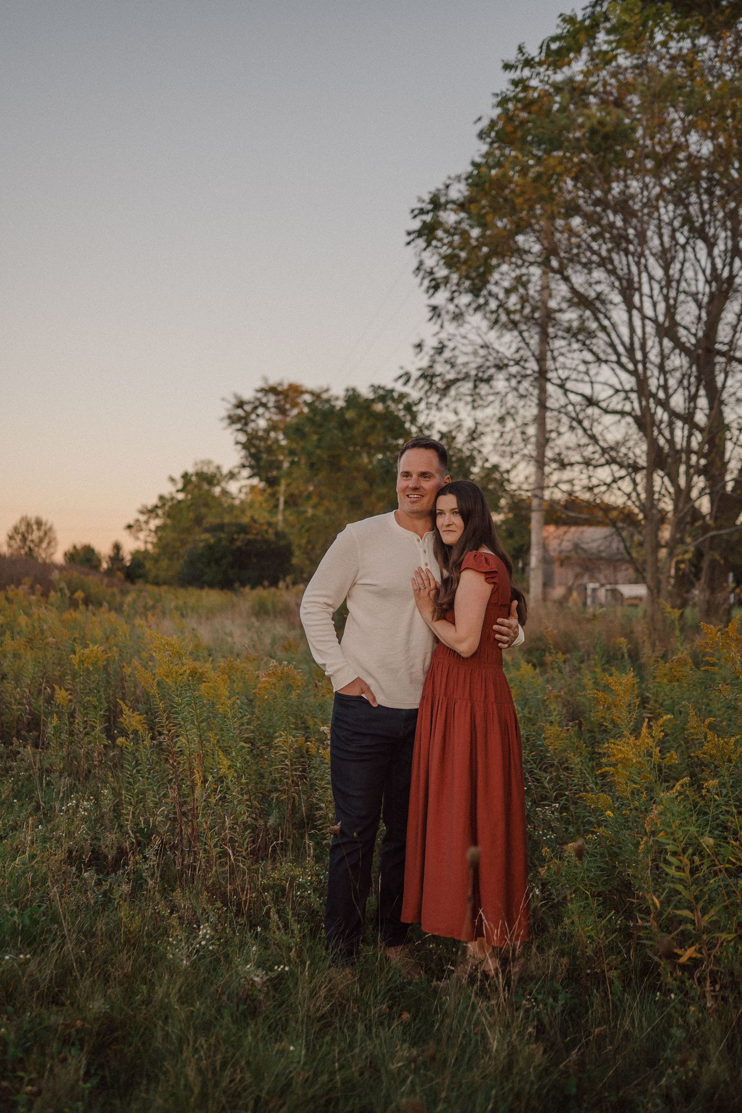 Romantic couple poses in wildflower field during sunset photoshoot.
