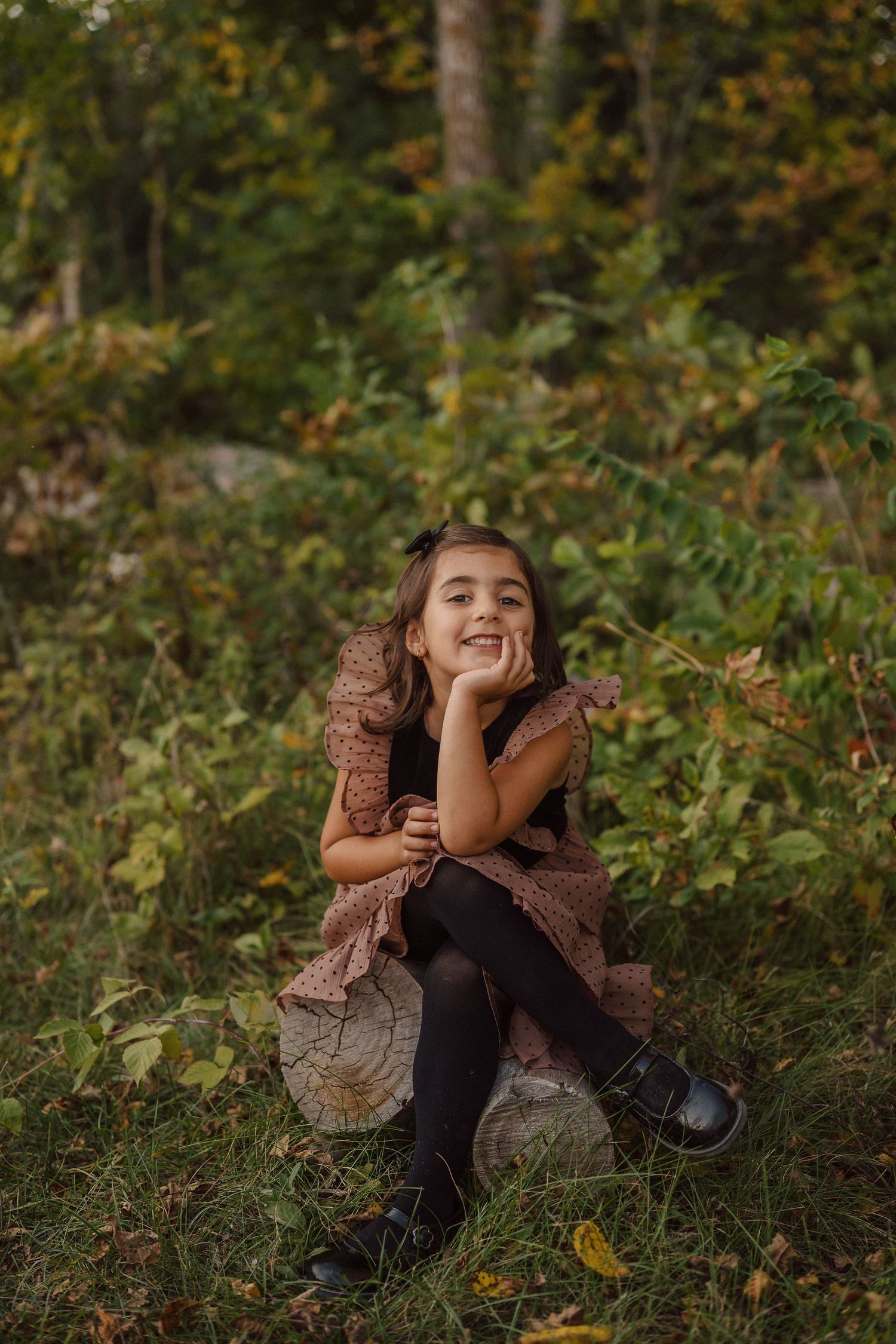 A series of candid outdoor portraits showing joyful expressions while sitting on the ground in an autumn forest setting.