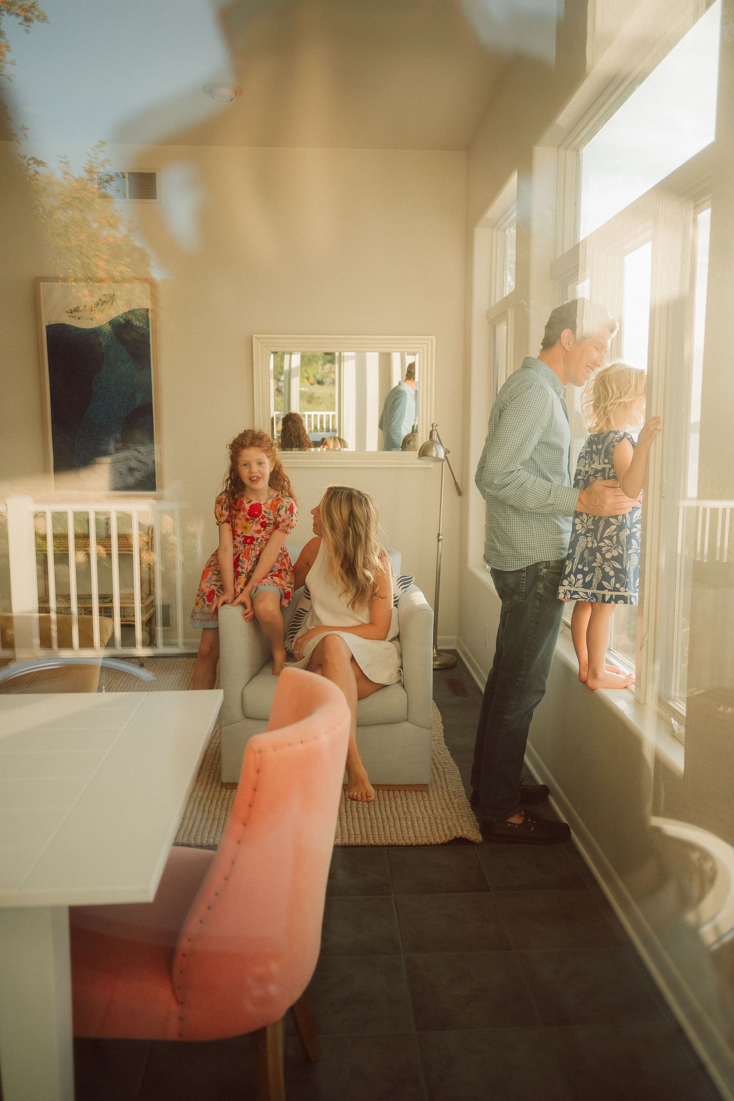 A casual family gathering in a bright sunlit room with modern furniture and large windows.