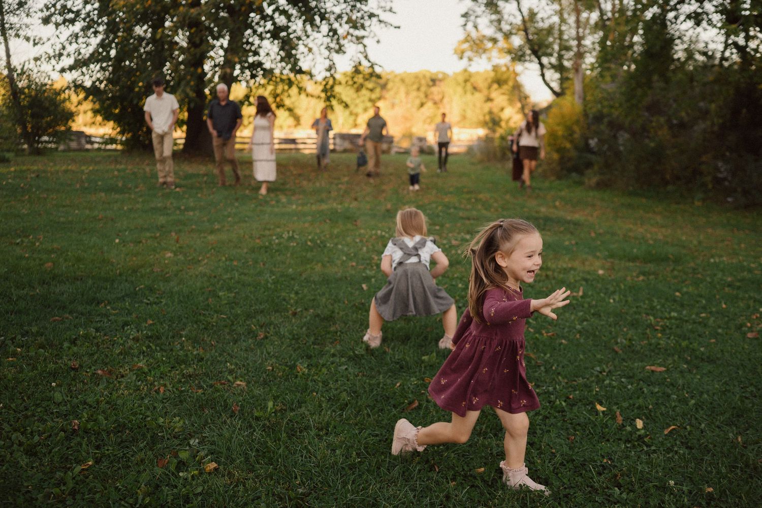 Group playing and running through an autumn field at sunset with trees in background.