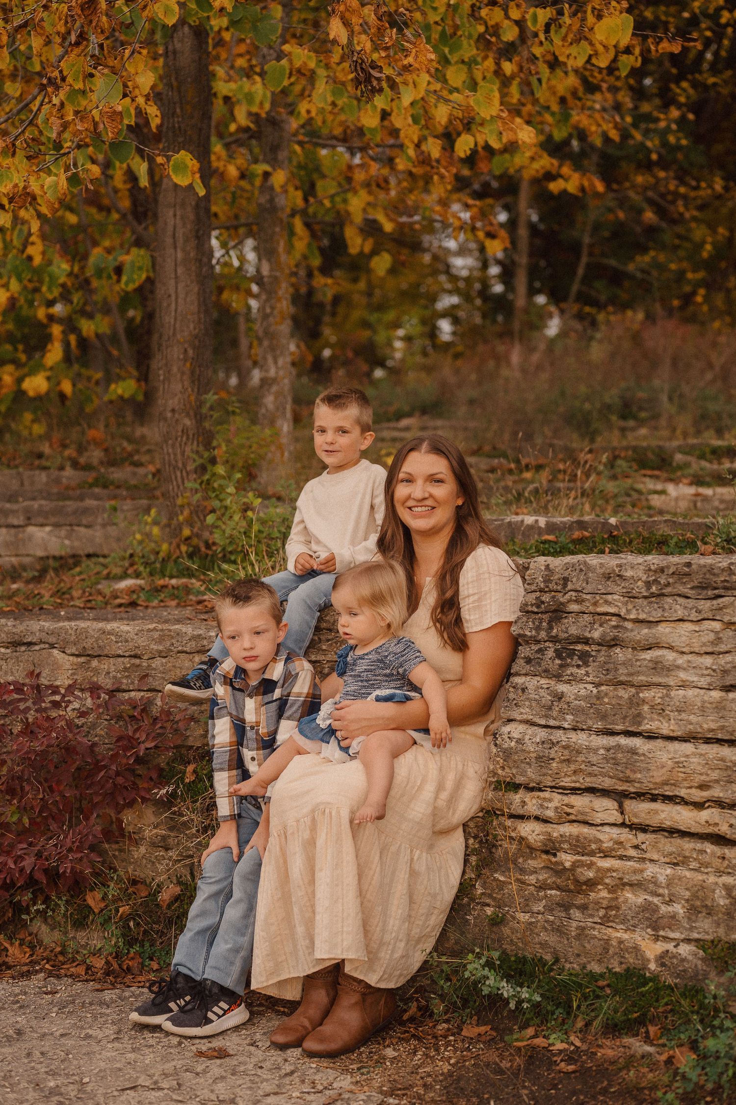 A group sits together on stone steps surrounded by fall foliage in warm autumn colors.