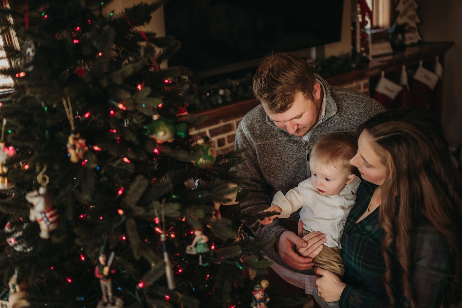 Family admiring their decorated Christmas tree together in a cozy living room setting.