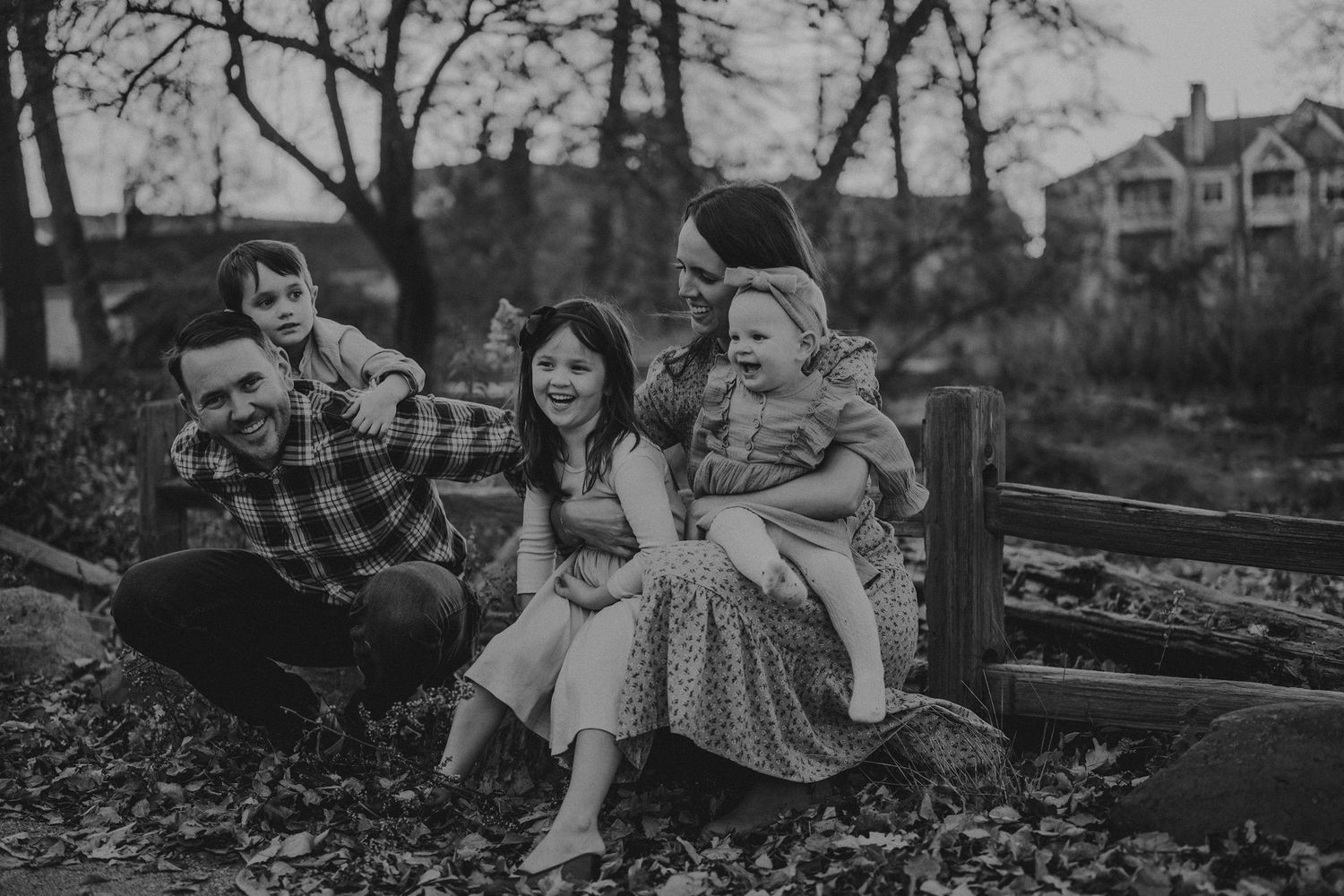 A black and white portrait of a family sitting together on rustic wooden steps.