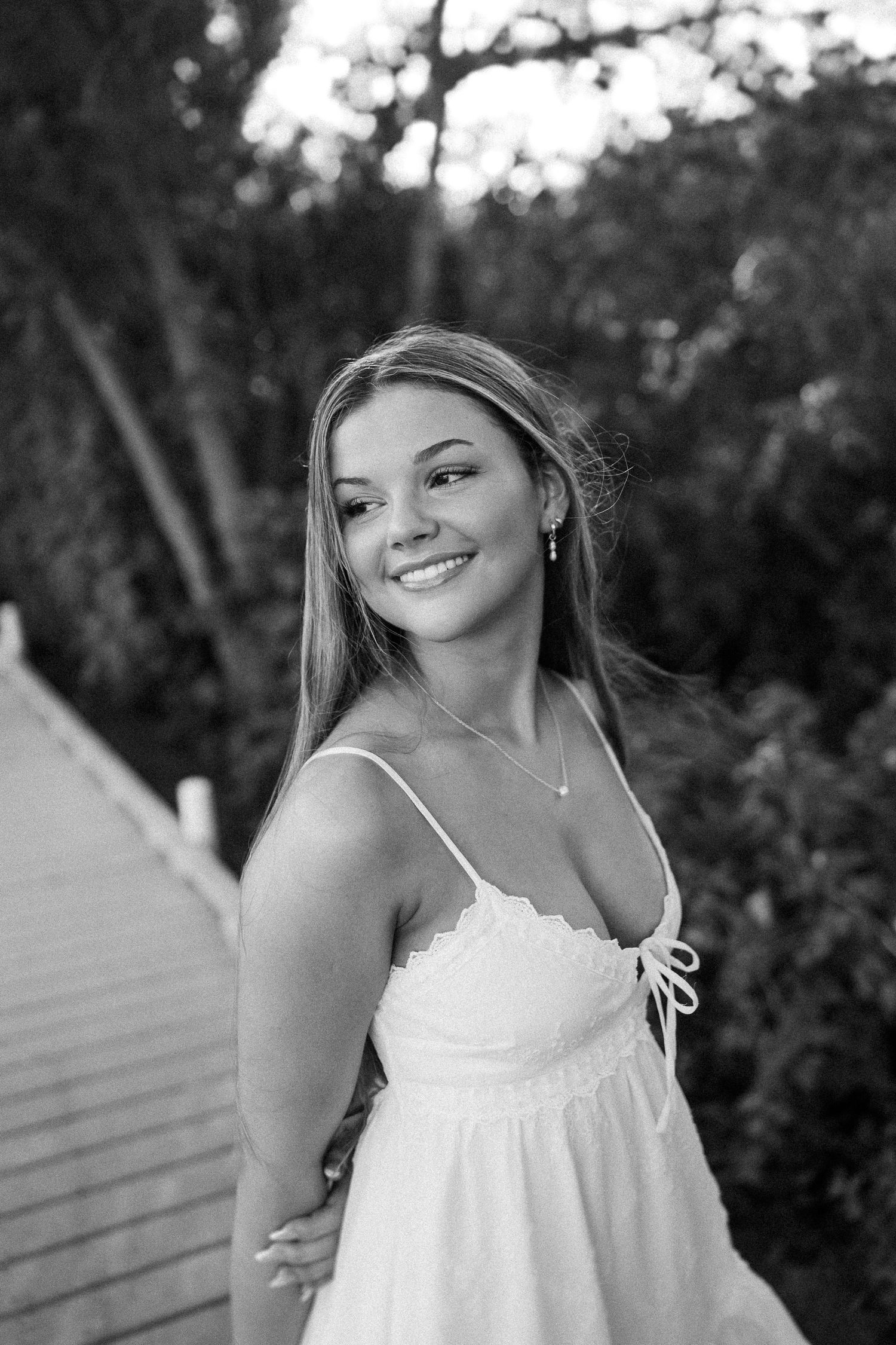 Summer portrait on wooden boardwalk wearing flowing white dress at golden hour.