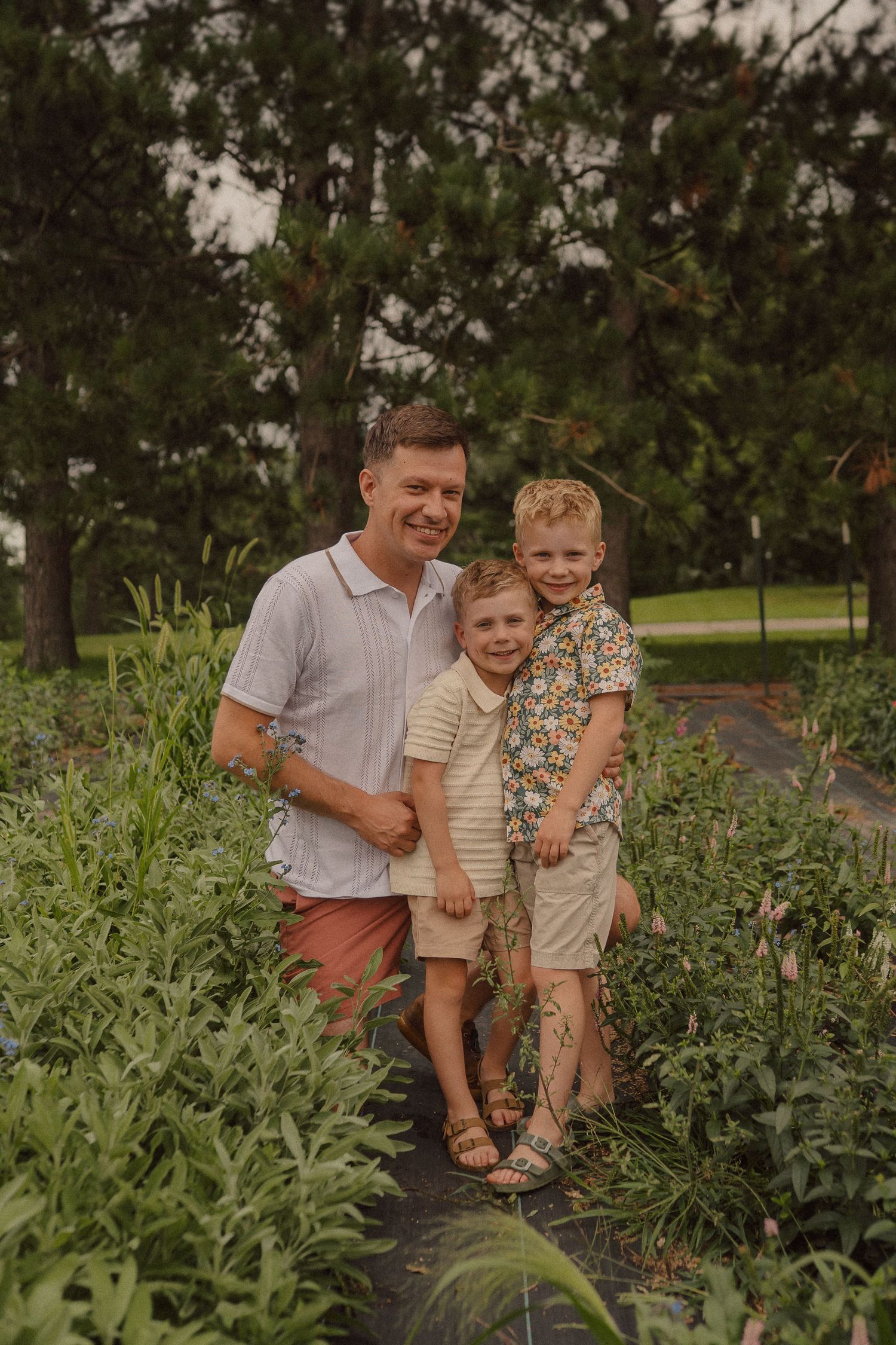 A joyful moment shared between family members outdoors among lush green plants during golden hour lighting.