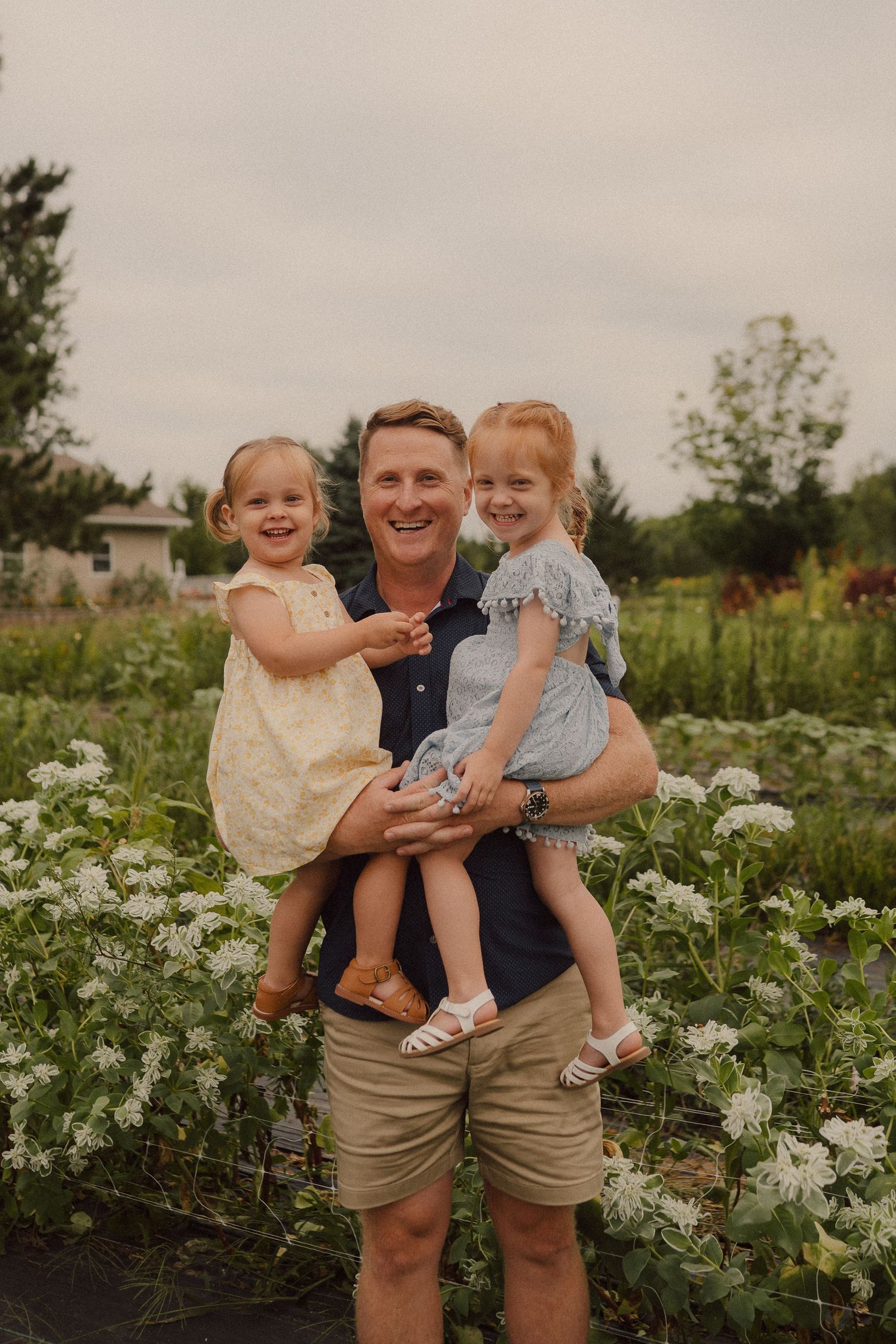 Candid family portrait series in a blooming flower garden on an overcast summer day.