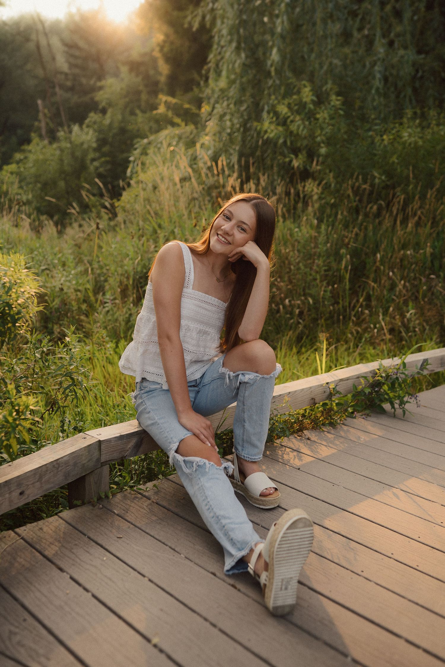 Casual outdoor portrait session on a wooden boardwalk during golden hour.
