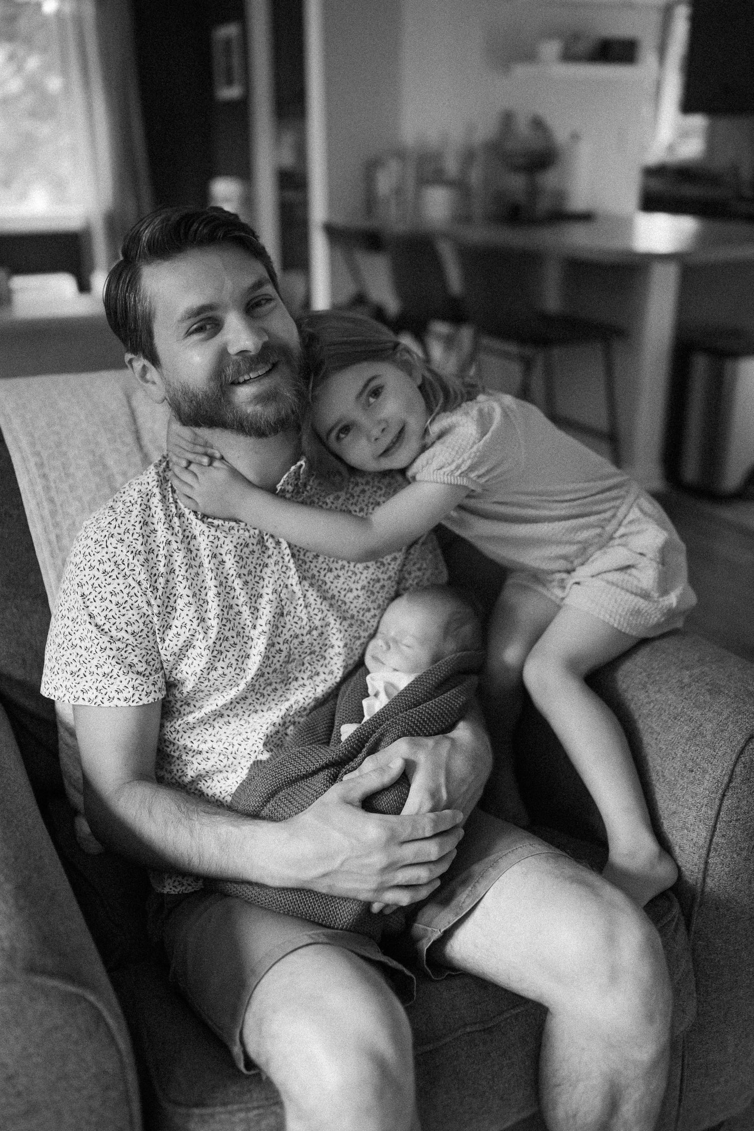 Black and white photo captures intimate moment on grey sofa in modern living room.