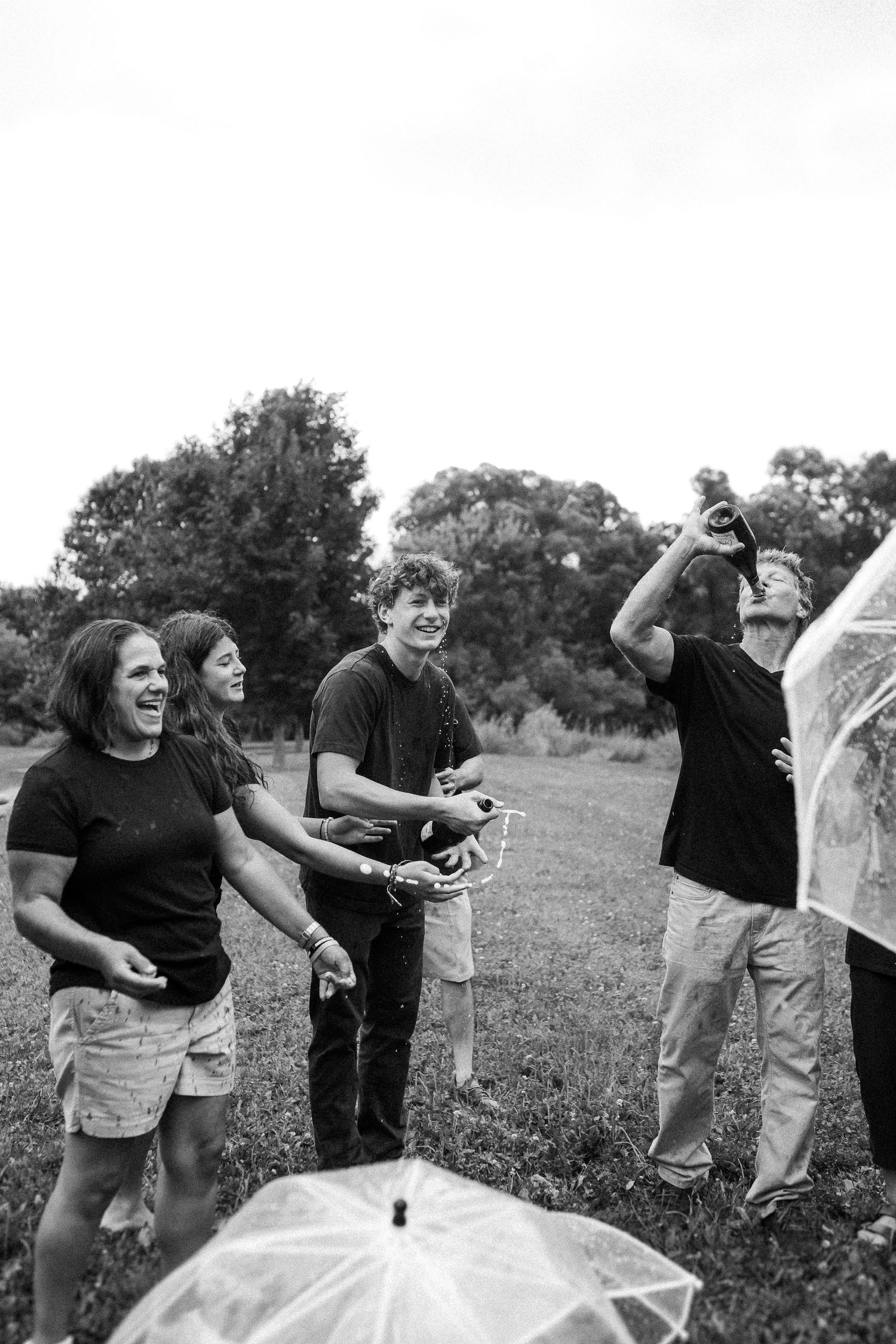 A black and white photo captures people playing and having fun outdoors in a grassy field.