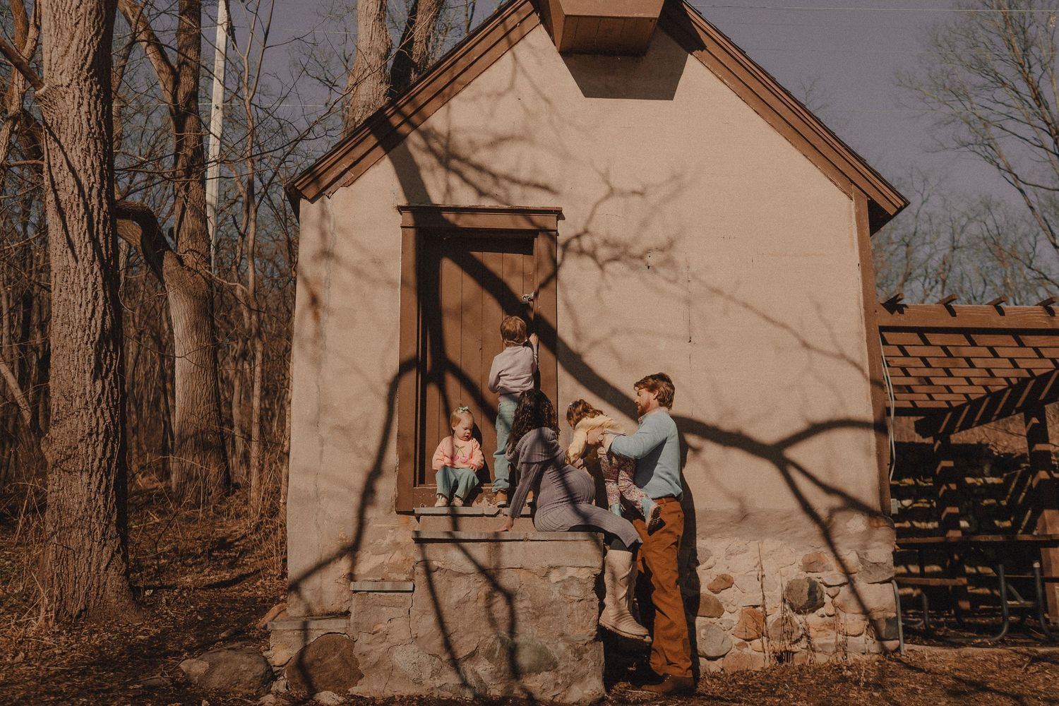 A rustic tan building nestled among bare winter trees with natural wood elements.