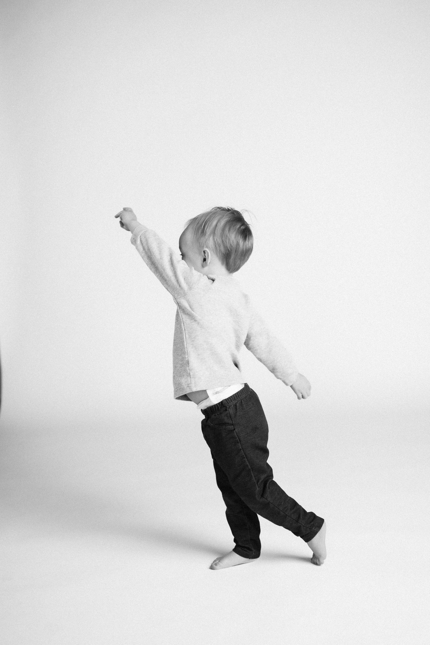 Black and white sequence of a child in motion showing playful jumping and movement against a white background.