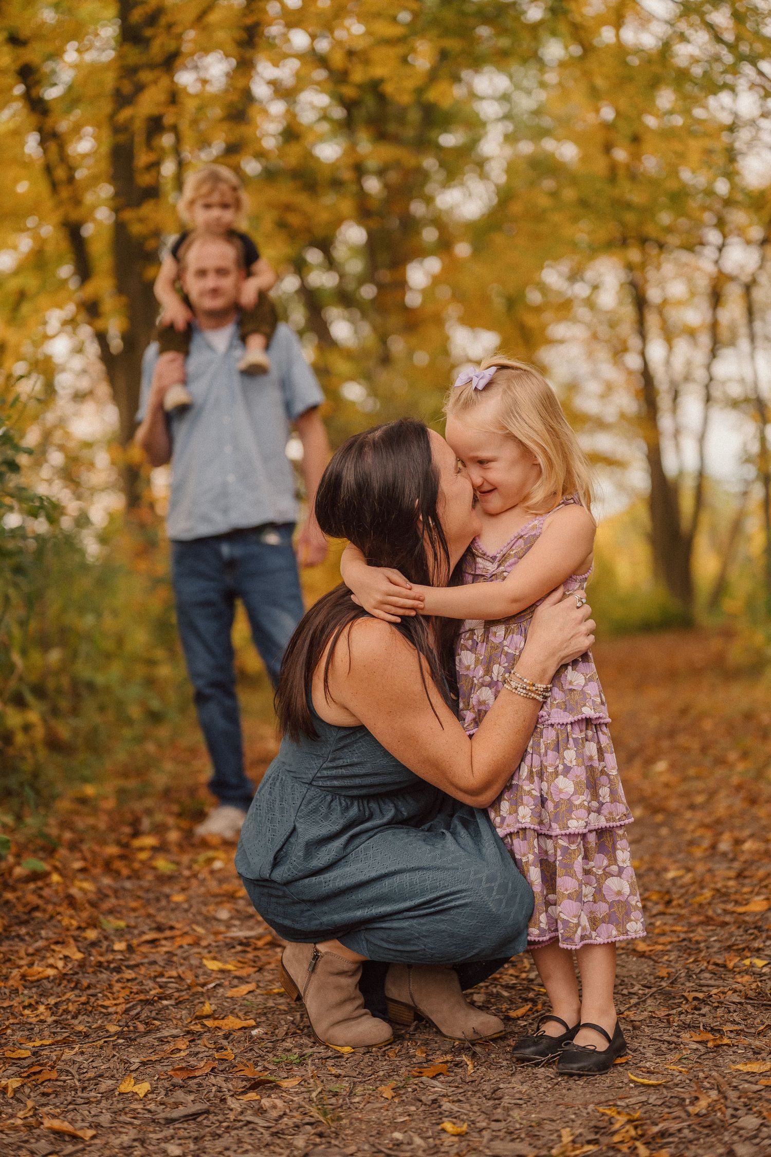 A tender moment shared between loved ones on a wooded path during fall season.