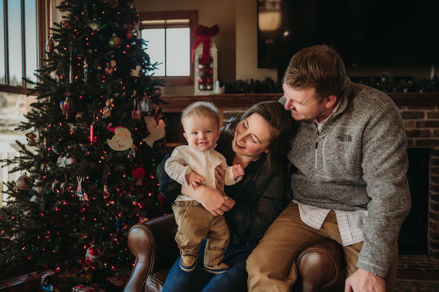 Family shares candid moment together near decorated Christmas tree indoors.