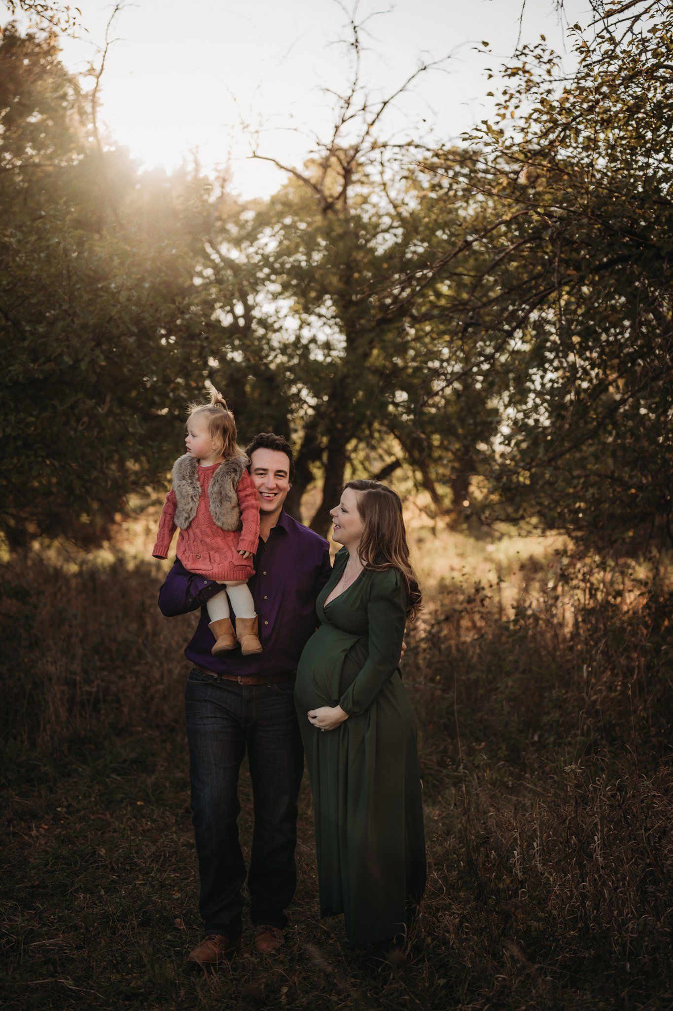 Family portrait at golden hour in a natural outdoor setting with autumn foliage.