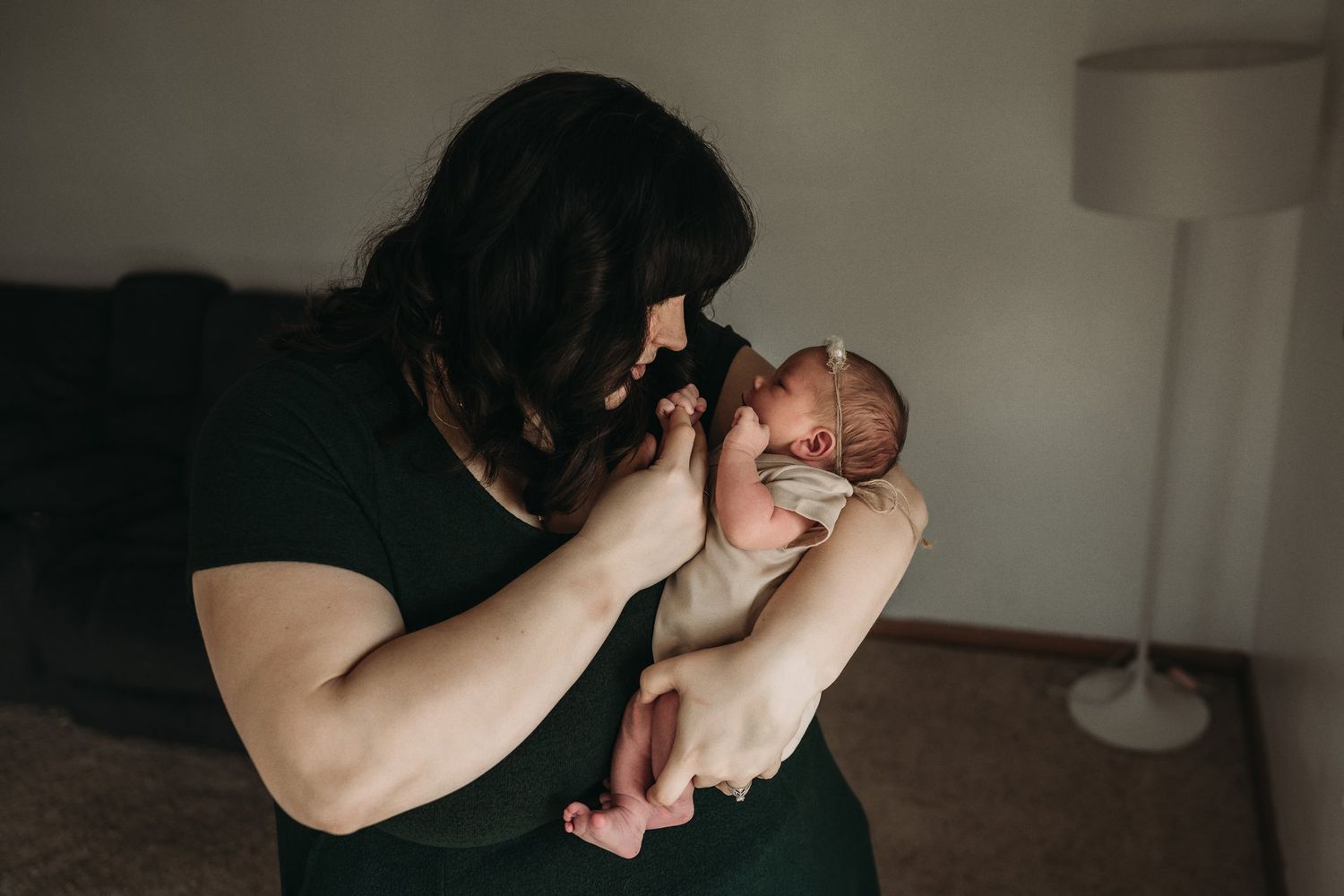 Photographer capturing newborn baby portrait in moody indoor lighting.