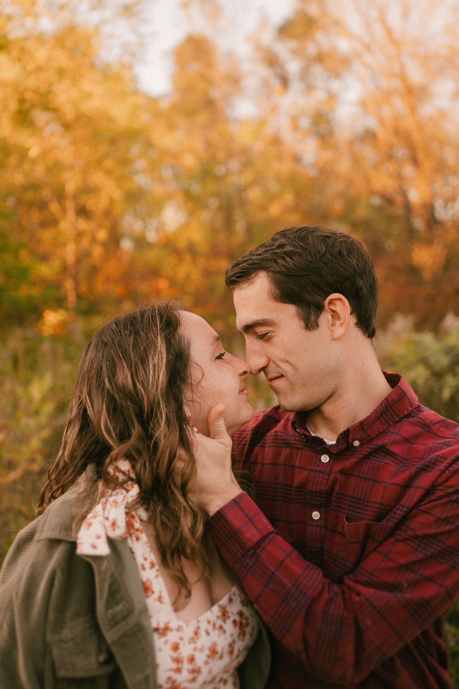 Intimate couple sharing romantic moment against autumn foliage background.